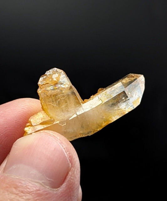 A translucent golden-yellow crystal cluster with sharp, faceted points and a natural, earthy base.