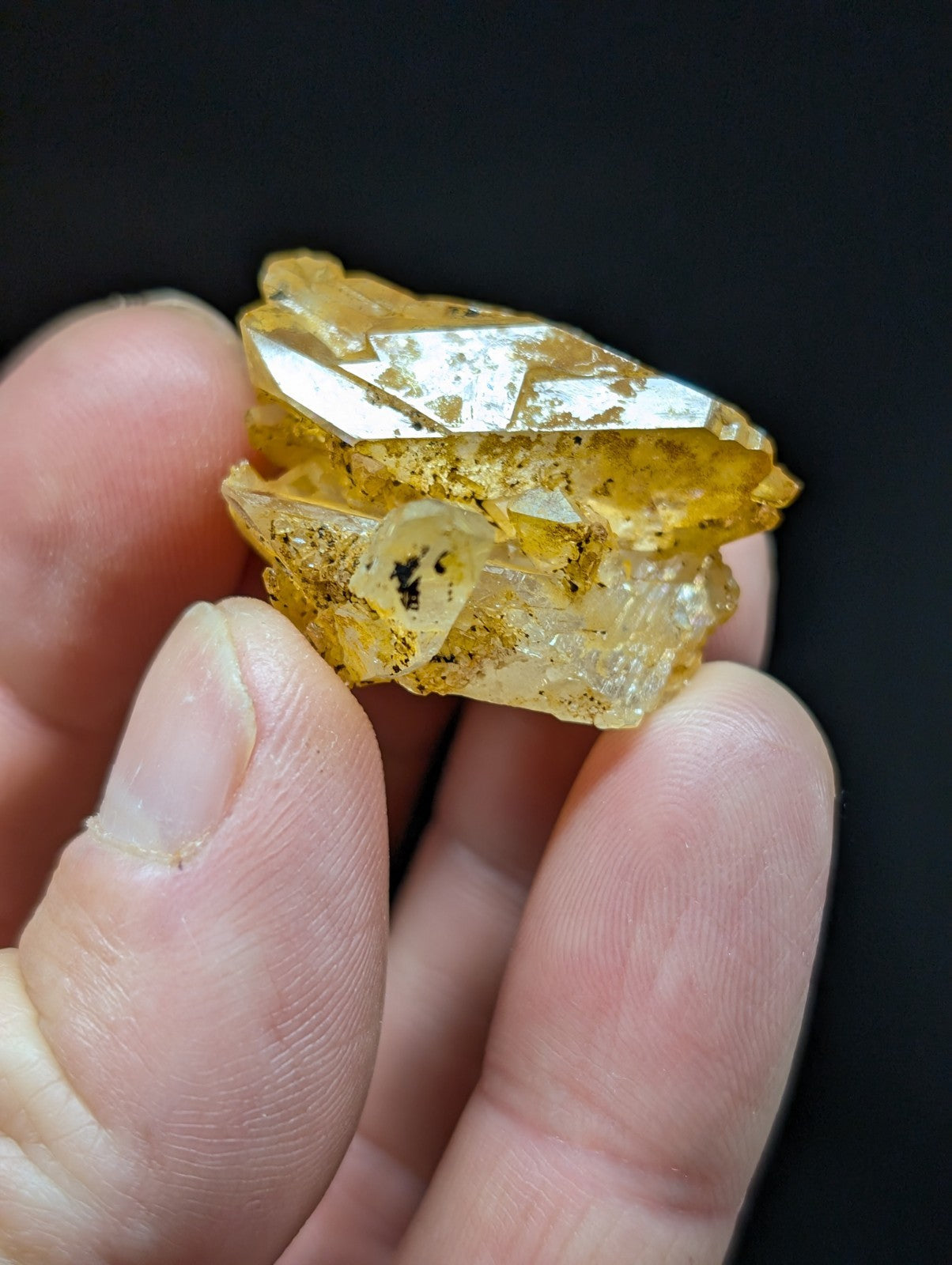 A translucent yellow crystal with a rough, jagged surface and embedded dark inclusions.