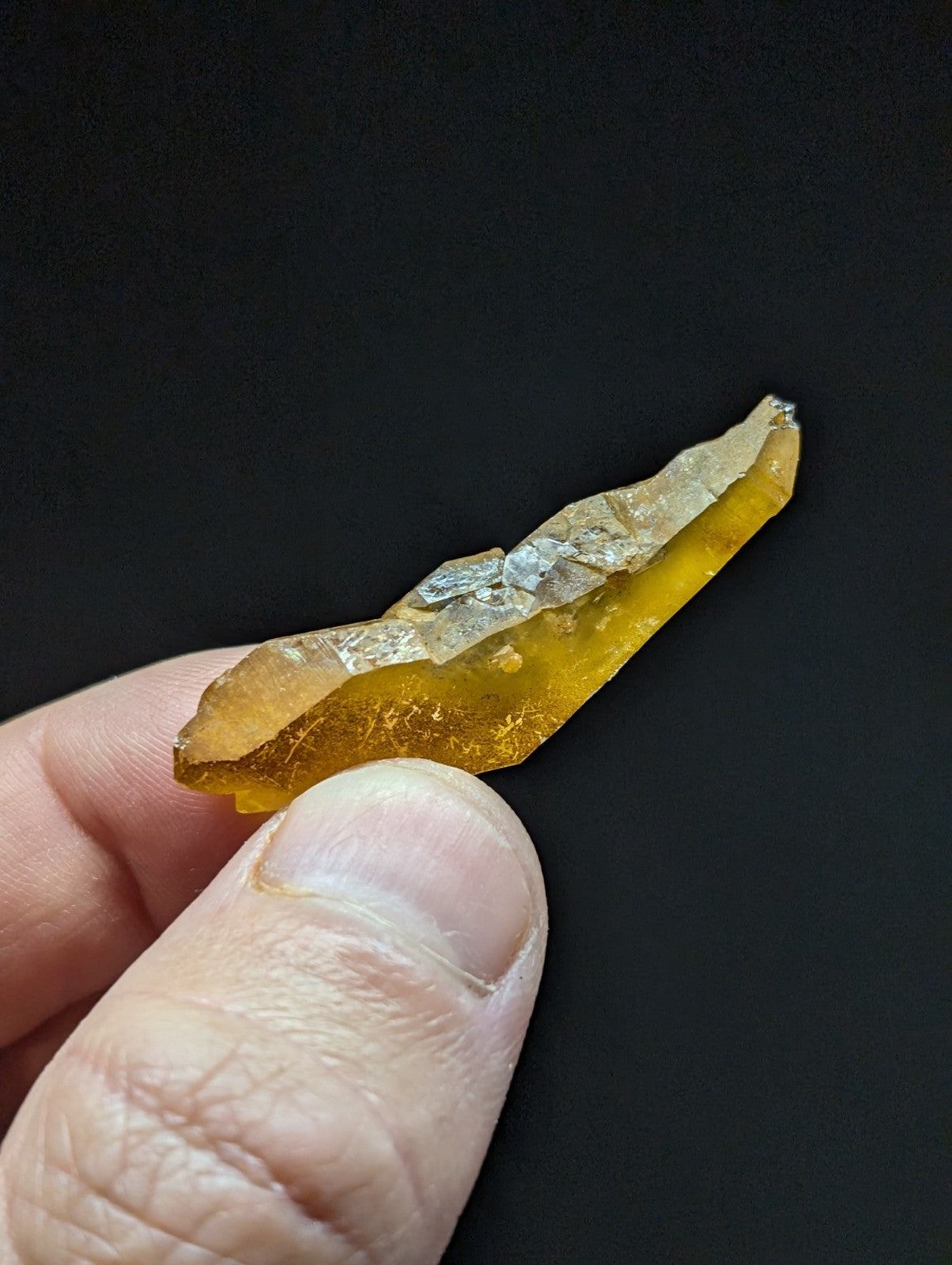 A translucent amber-colored fossilized resin fragment with a jagged, irregular edge and subtle internal inclusions.