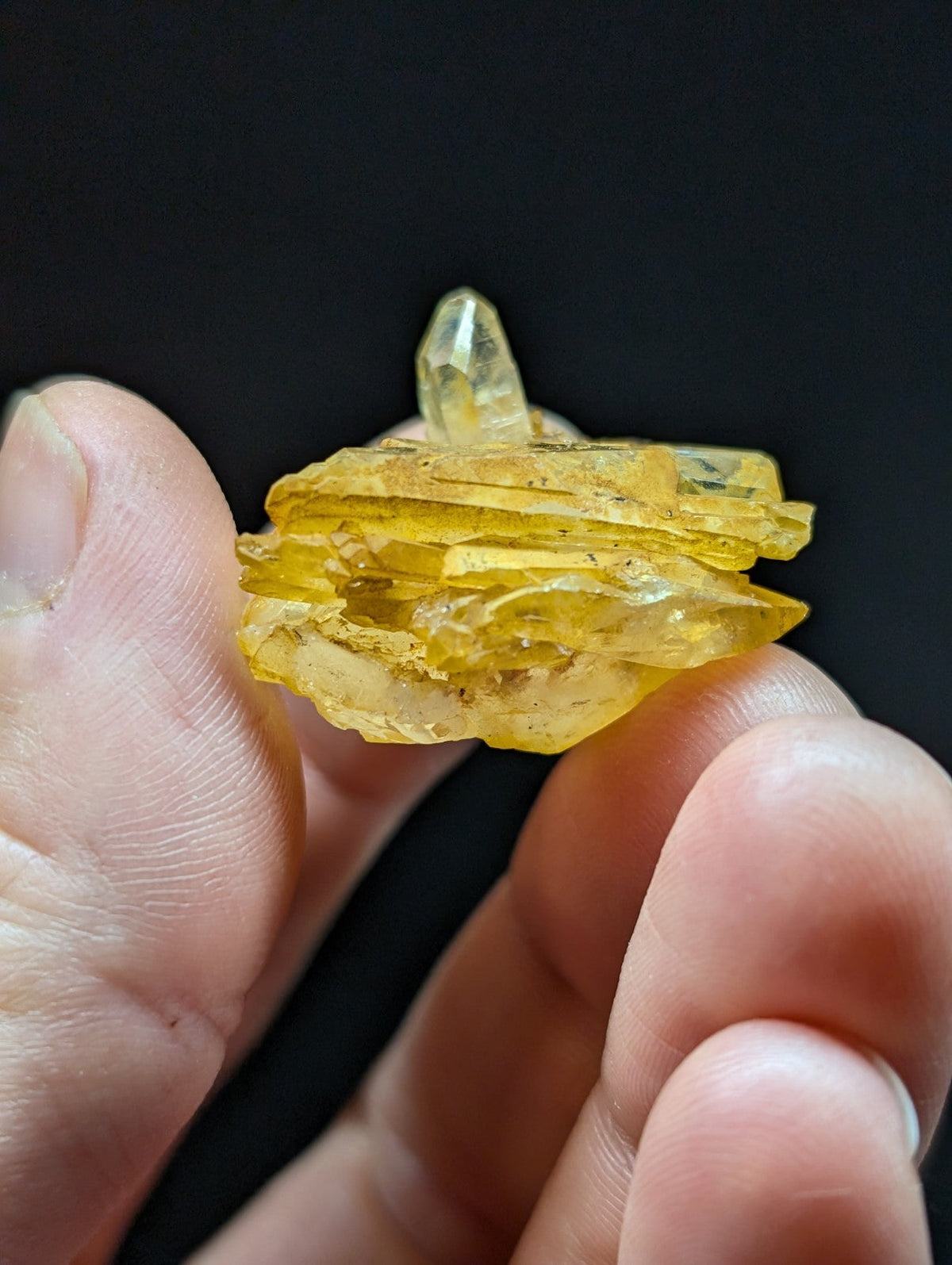 A translucent yellow crystal cluster with sharp, layered facets and a pointed tip.