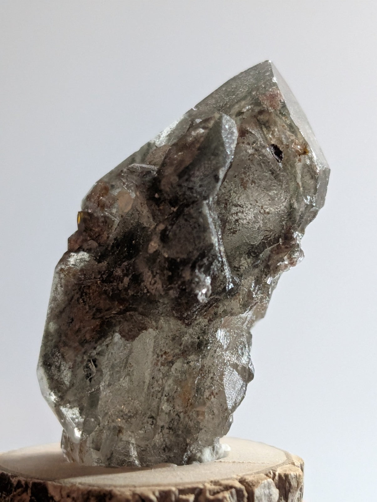A translucent gray crystal with a rough, jagged surface and visible internal inclusions.