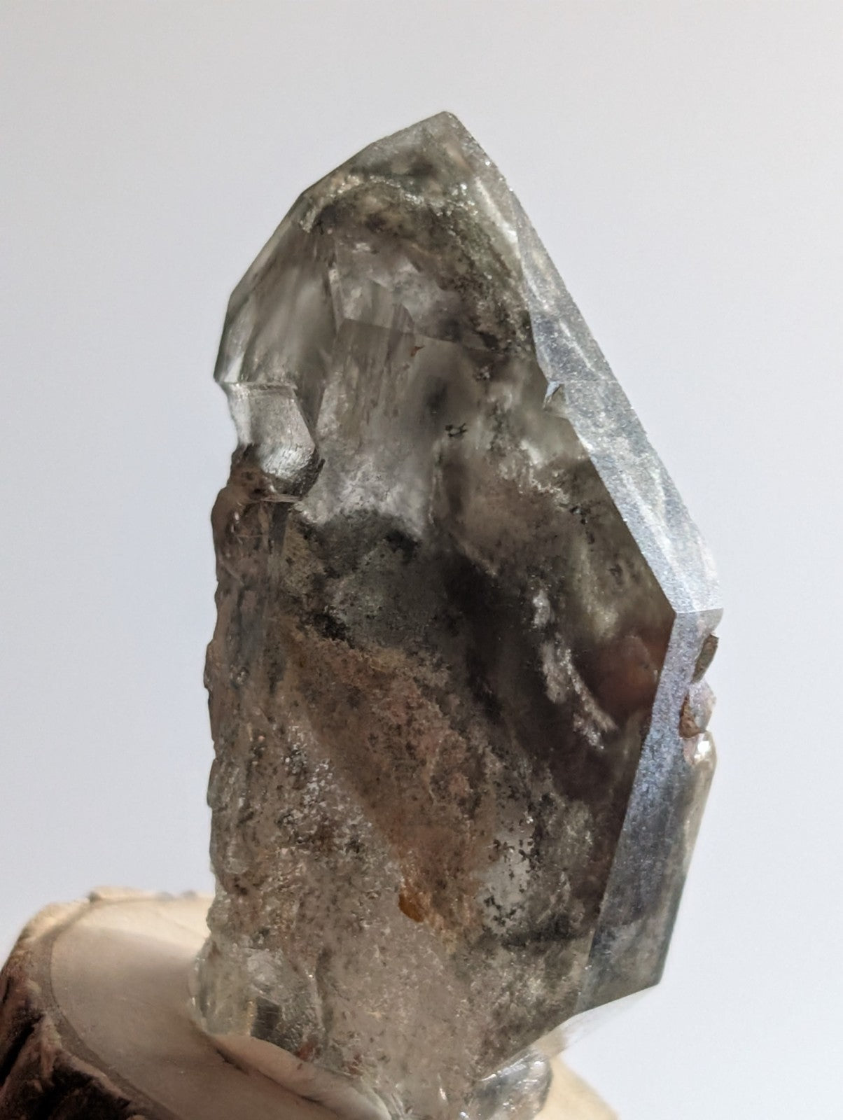 A translucent gray quartz crystal with a faceted, pointed top and rougher base.