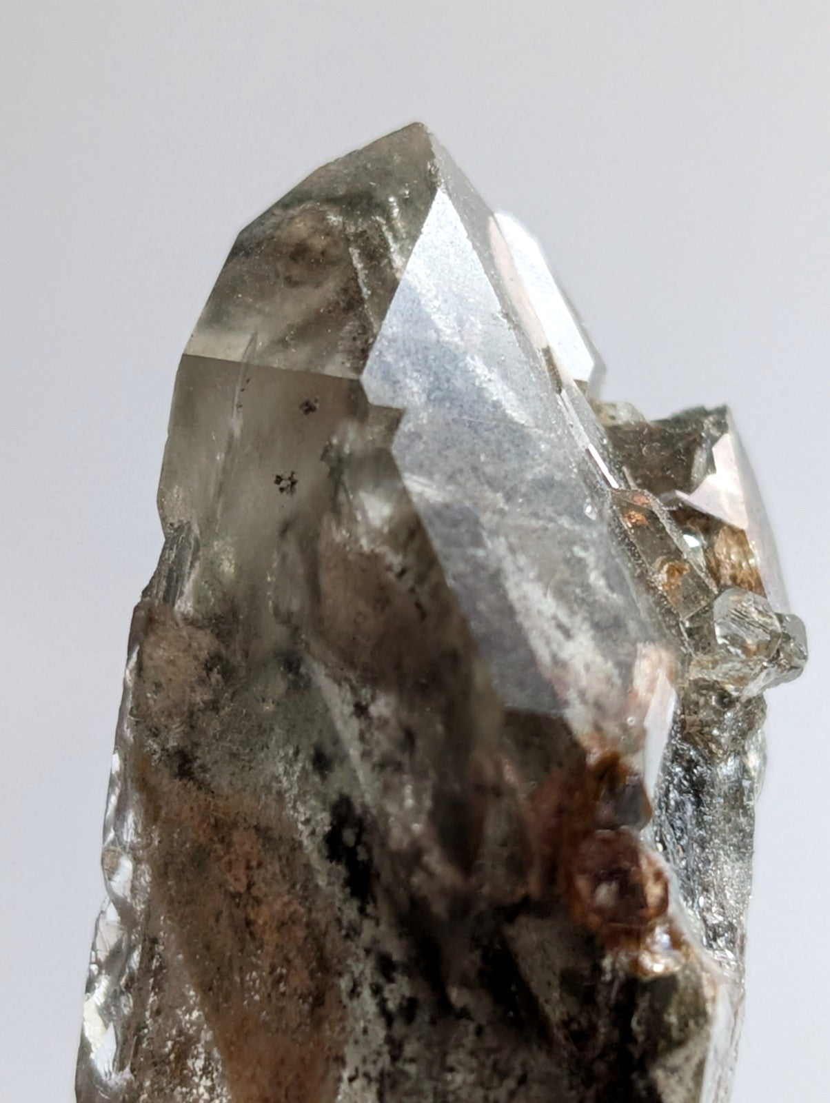 A translucent, faceted quartz crystal with a clear to smoky gray hue and natural inclusions.