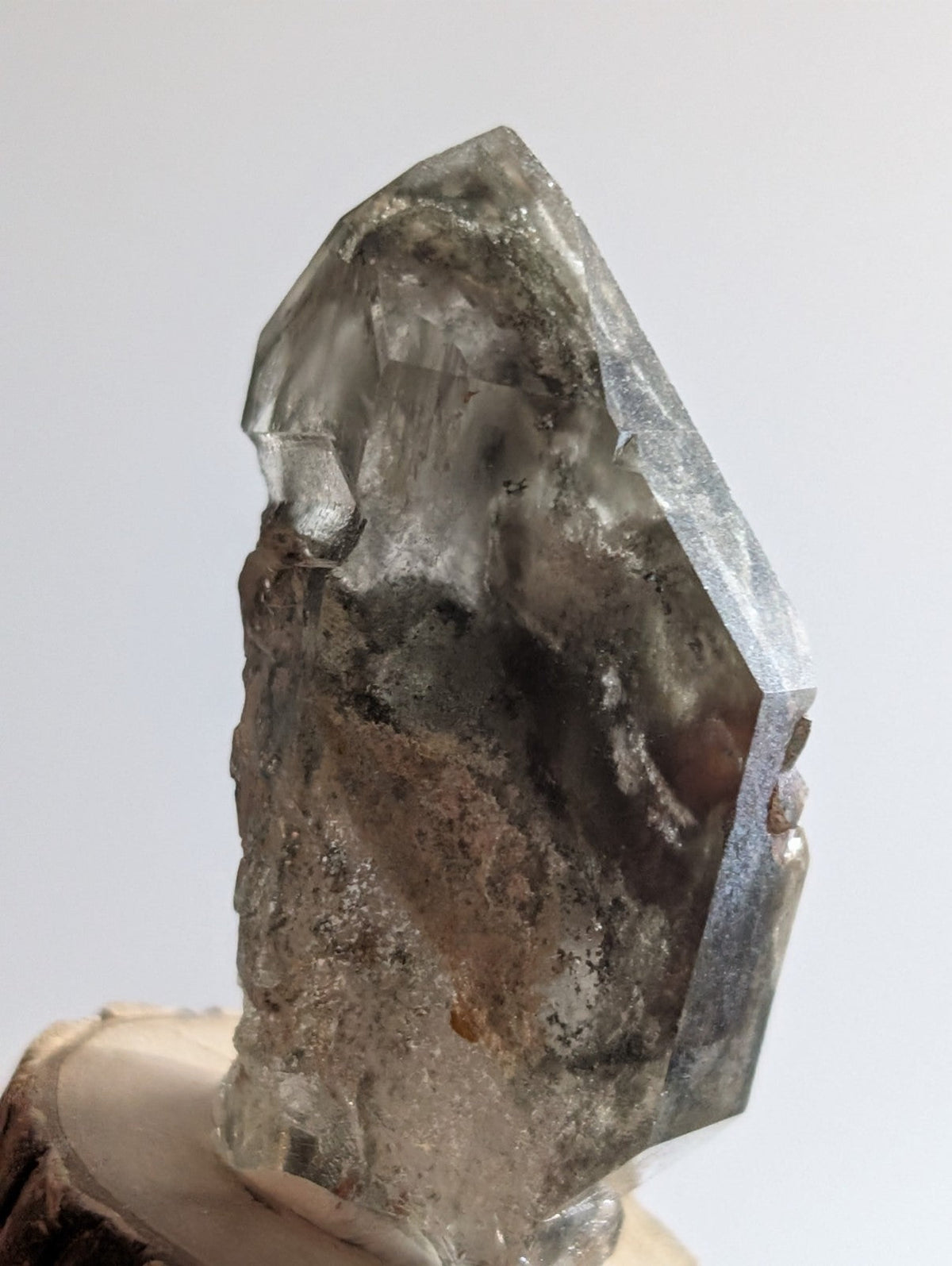 A translucent gray quartz crystal with a faceted, pointed top and rougher base.