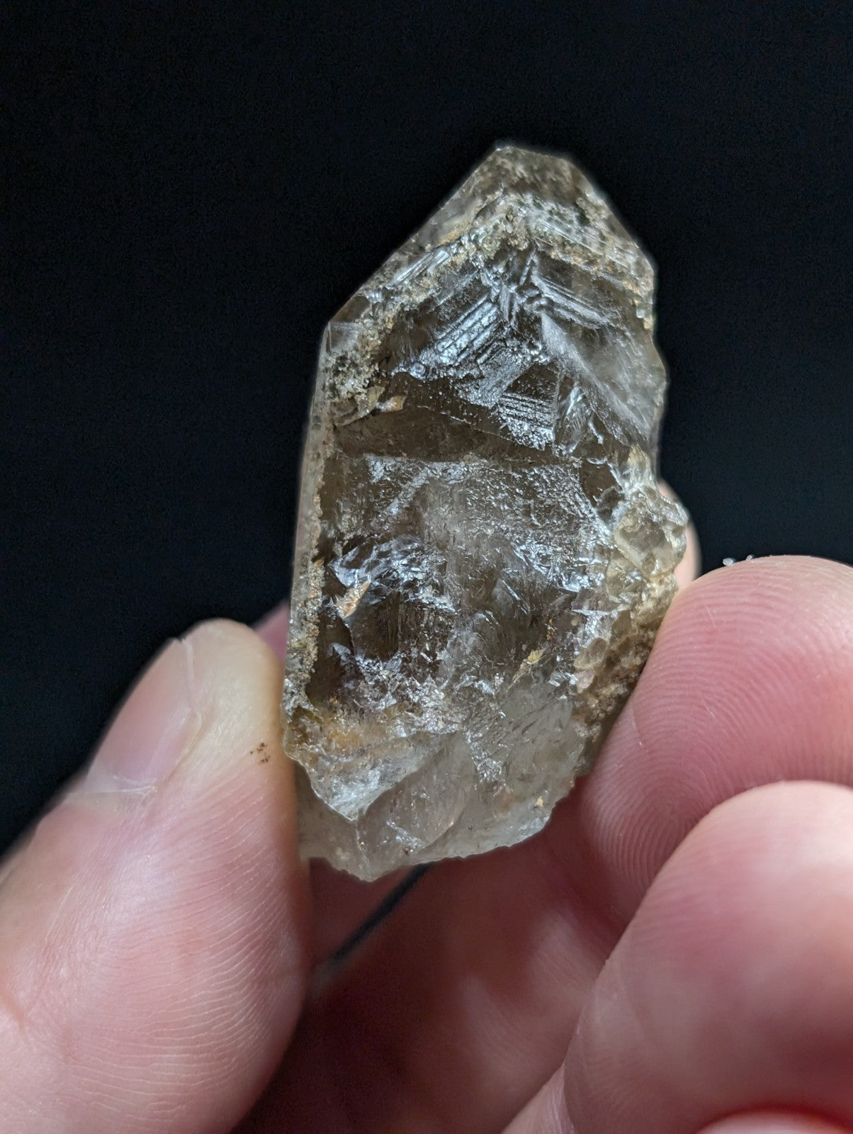 A translucent, smoky quartz crystal with natural facets and a rough, earthy surface.