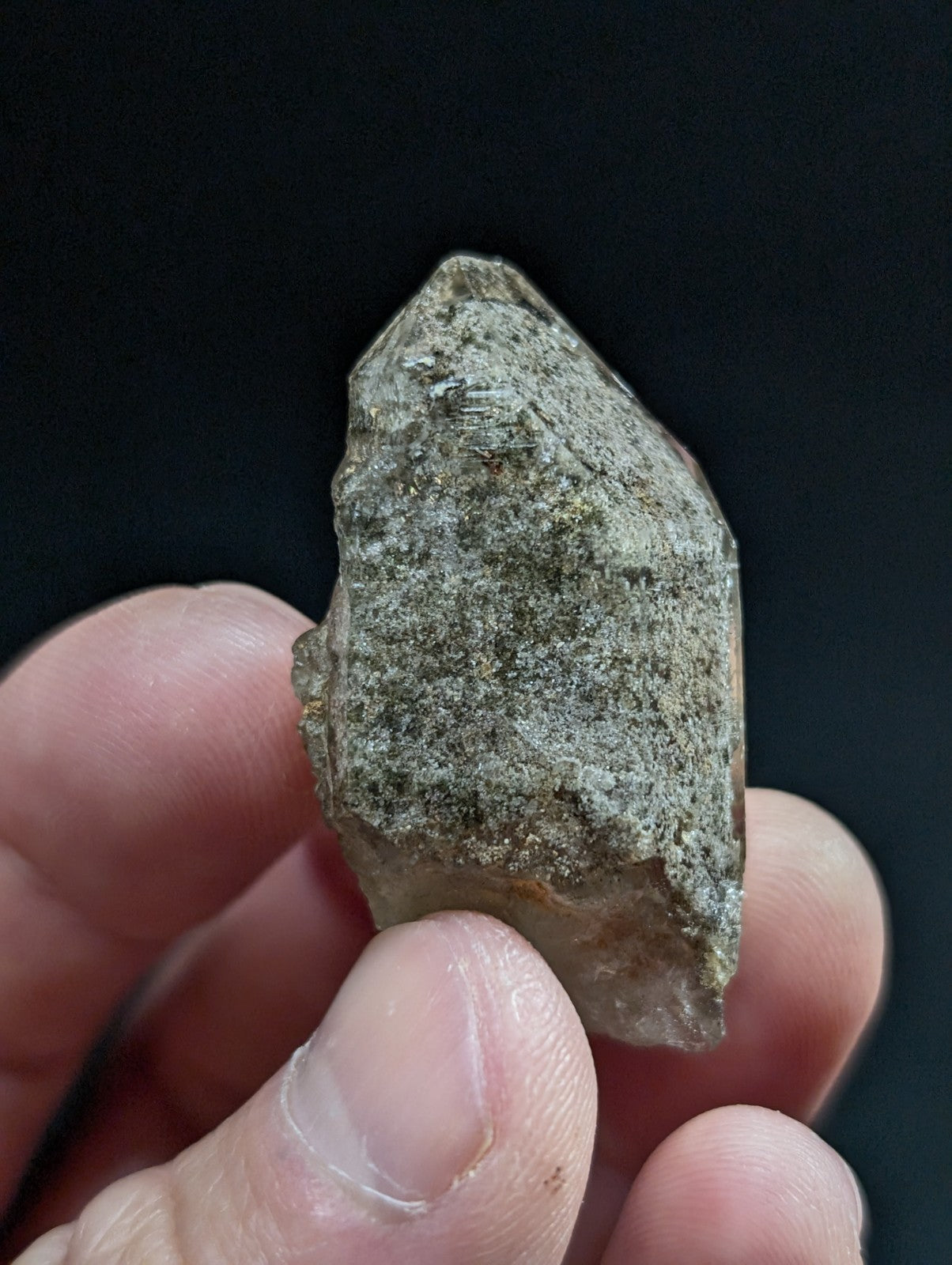 A rough, translucent quartz crystal with a grayish-green hue and natural facets.