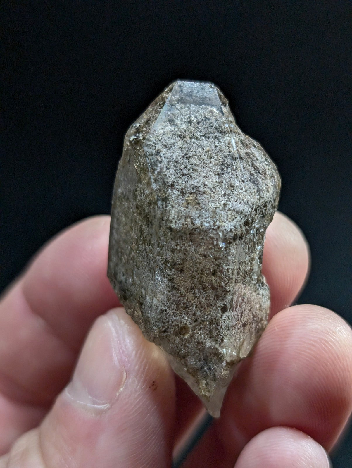 A rough, translucent quartz crystal with a grayish-brown matrix and pointed tips.