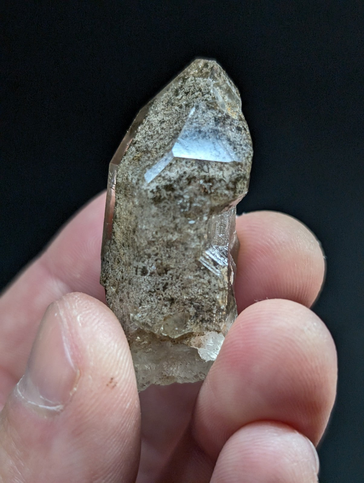 A translucent, smoky quartz crystal with a pointed tip and visible internal inclusions.