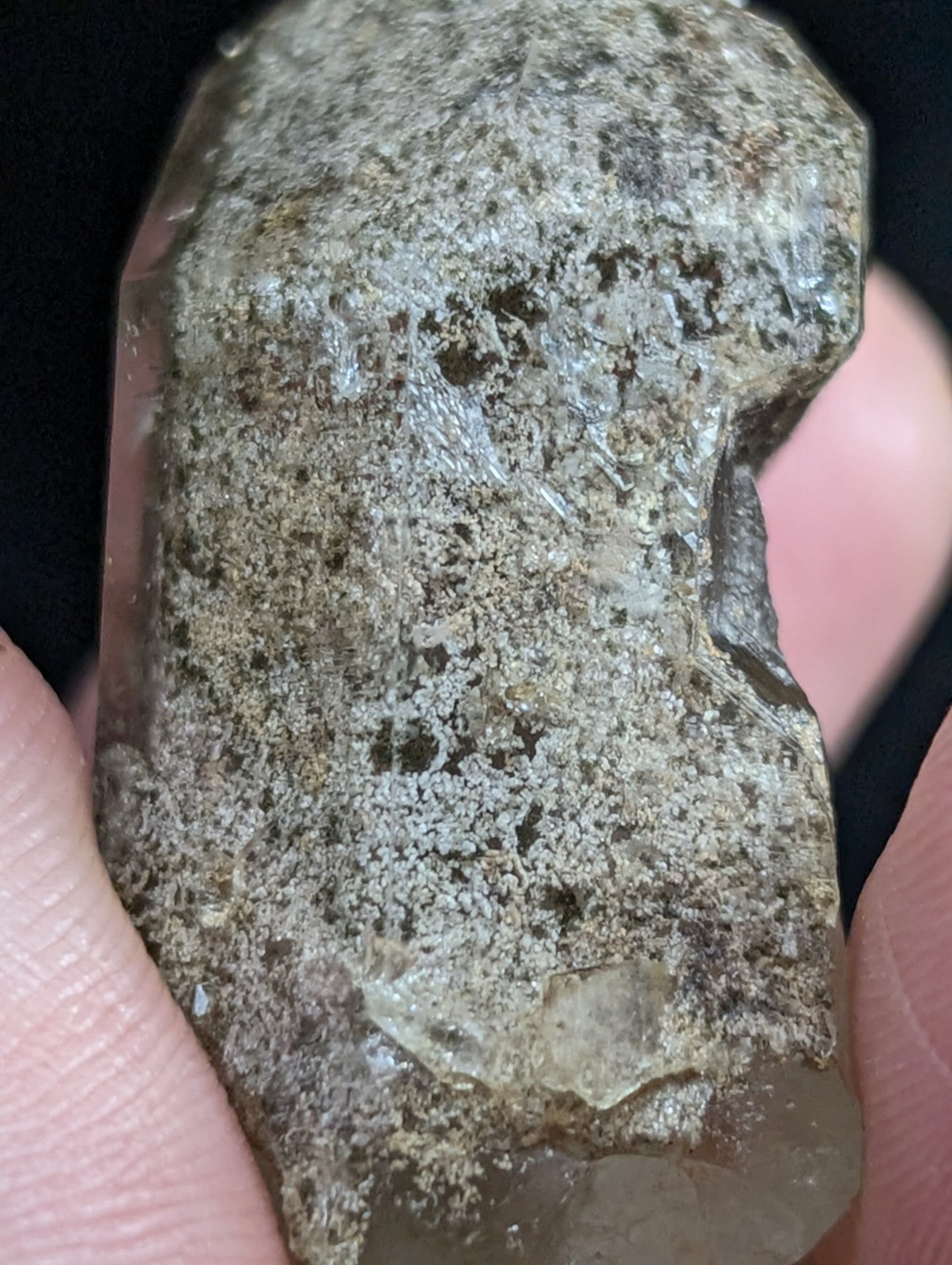 A rough, translucent quartz crystal with a mottled gray and brown surface texture.