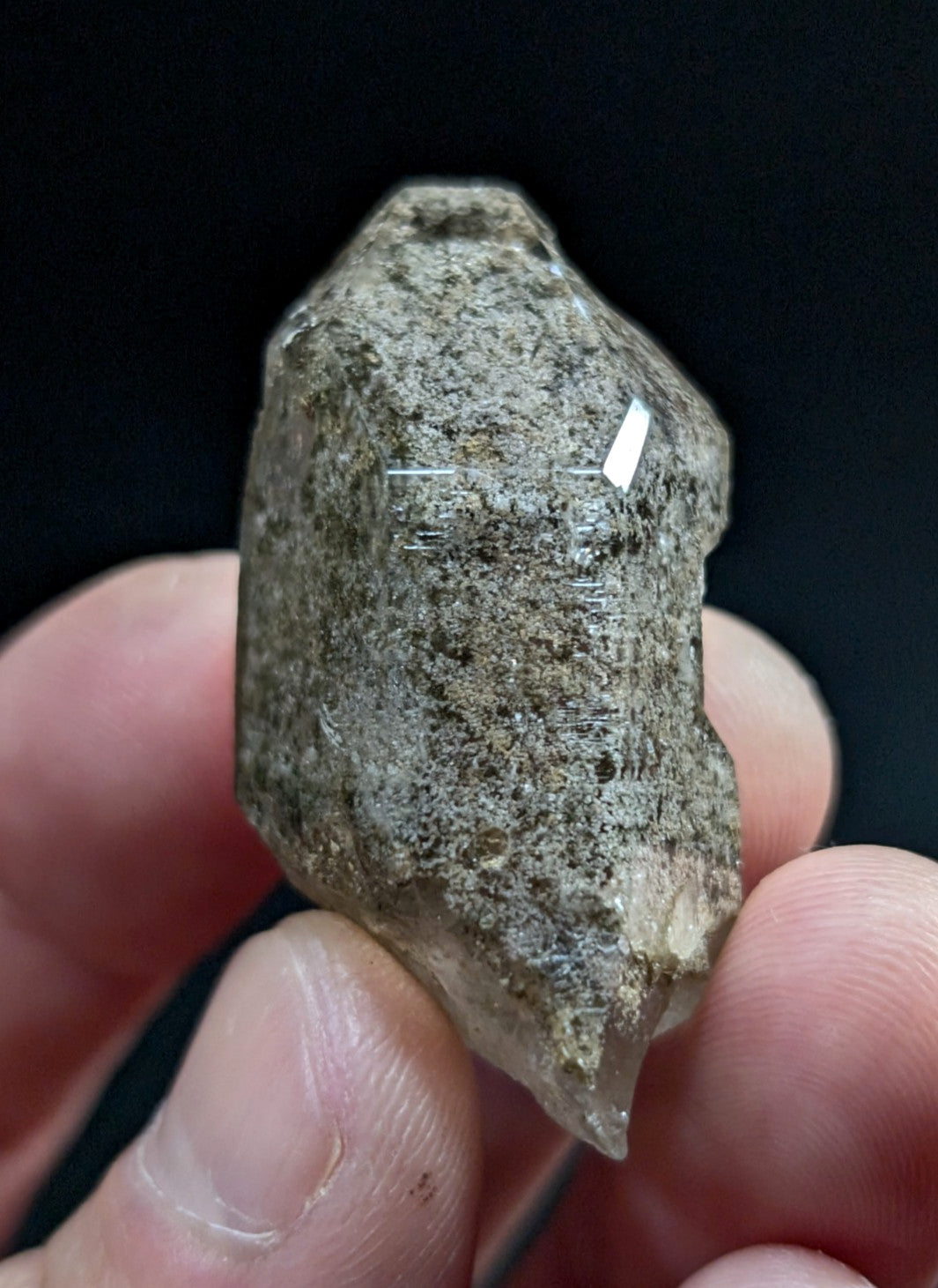 A rough, translucent quartz crystal with a grayish-brown matrix and visible internal striations.
