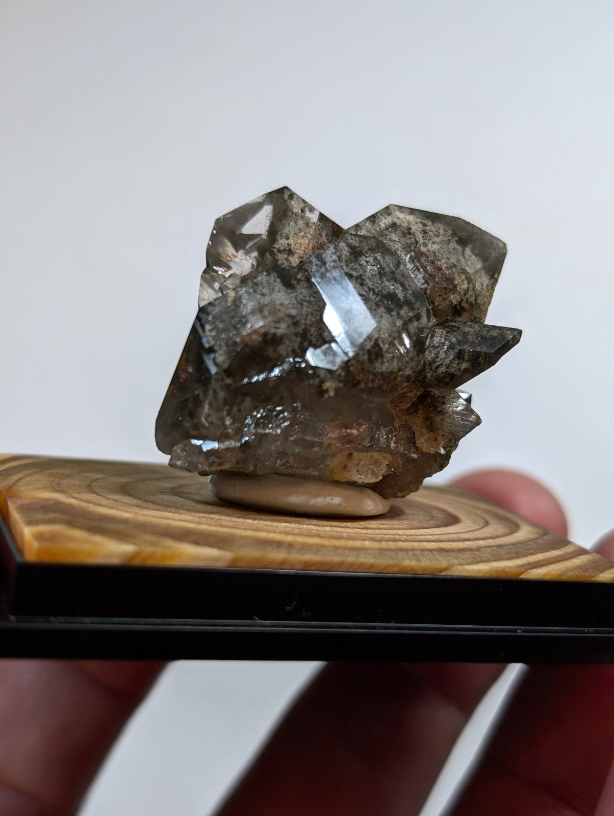 A translucent gray crystal cluster with sharp, faceted edges and a rough, earthy base.