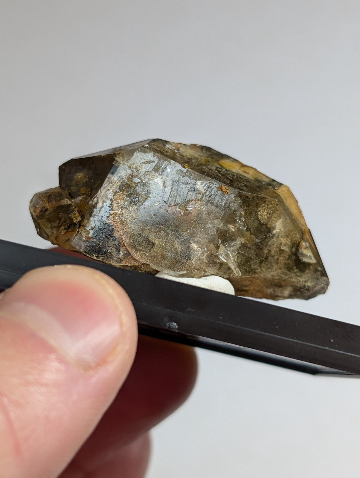 A rough, translucent brown crystal with a metallic sheen and visible internal inclusions.