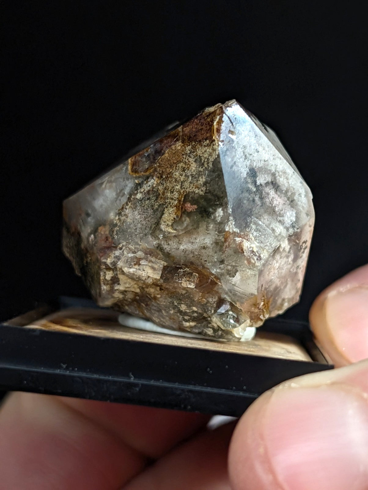 A translucent, faceted quartz crystal with earthy brown and gray inclusions.