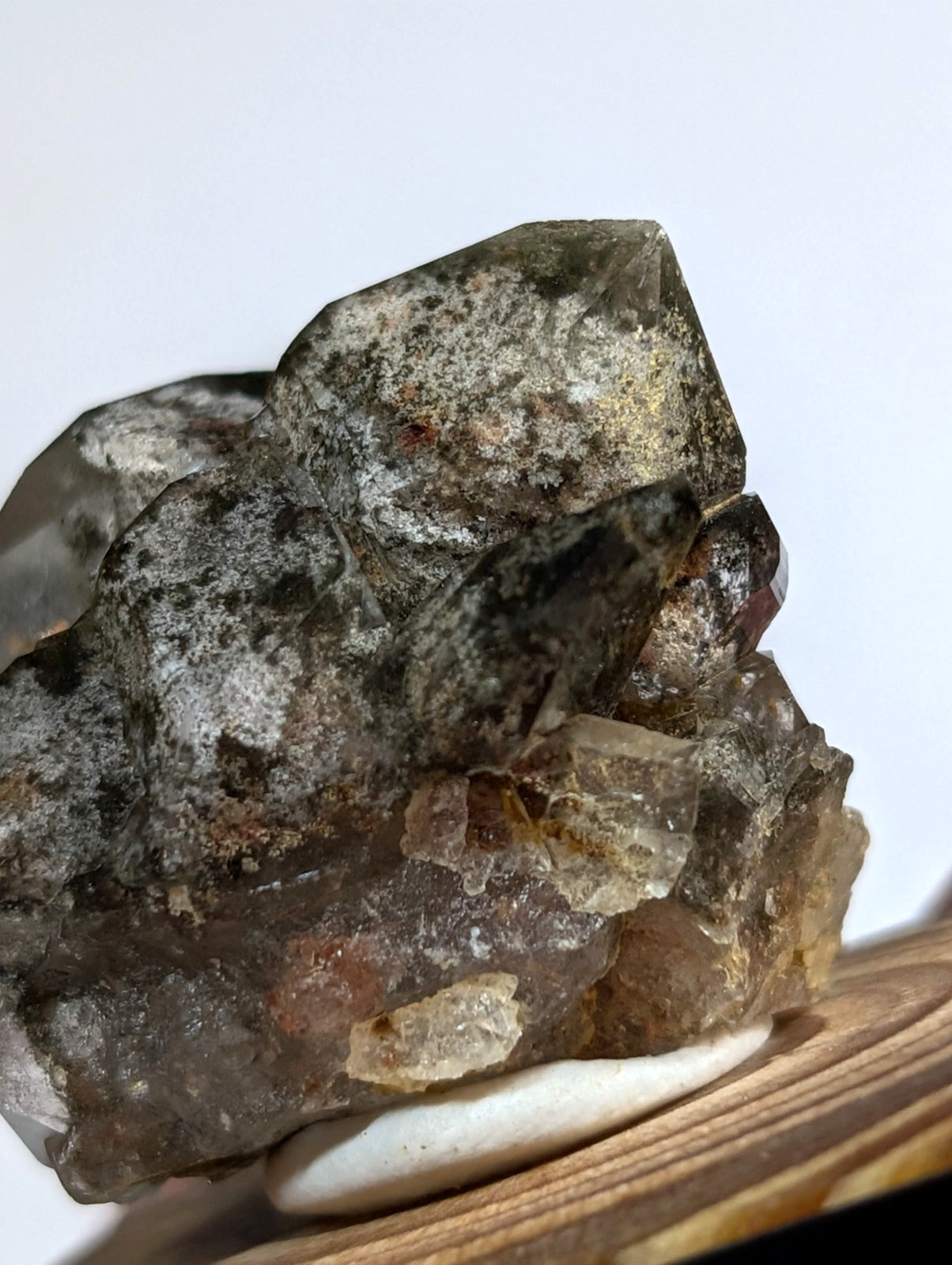 A cluster of smoky quartz crystals with a translucent, earthy brown and gray hue, showcasing natural facets and mineral inclusions.