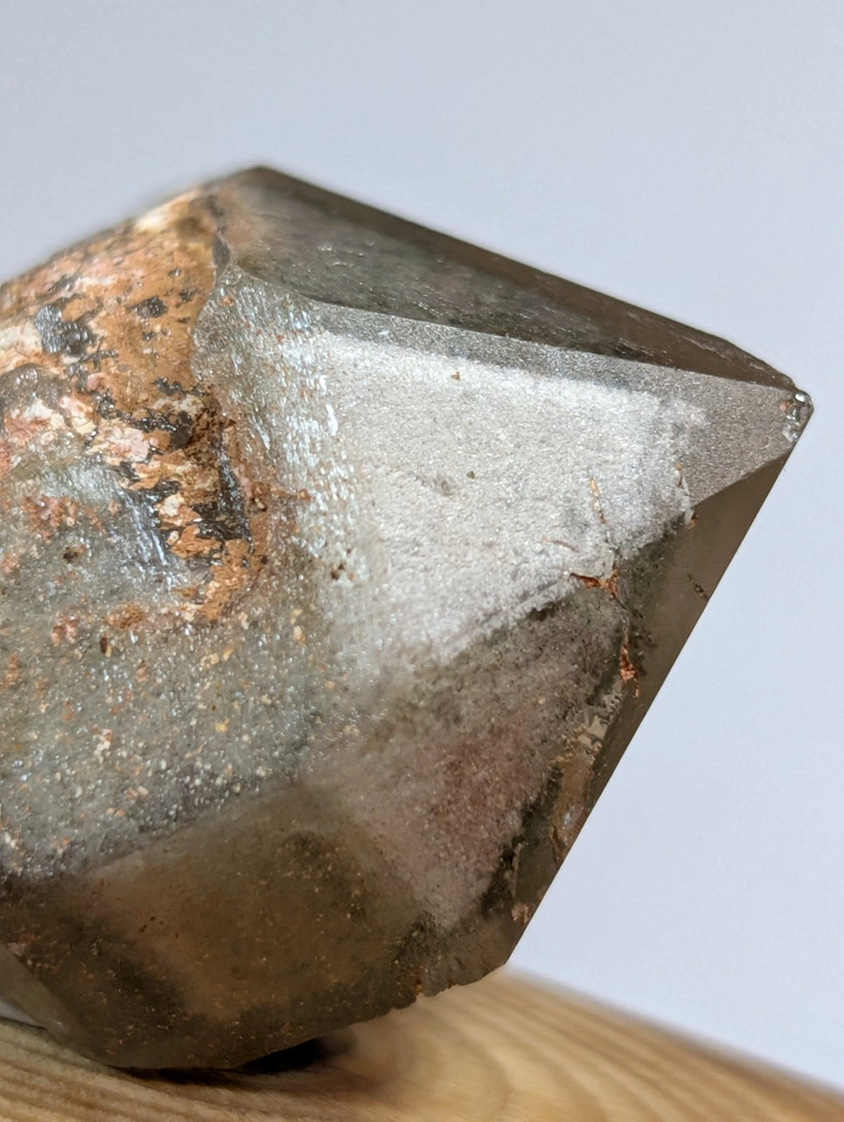 A translucent, faceted smoky quartz crystal with earthy brown and gray tones.