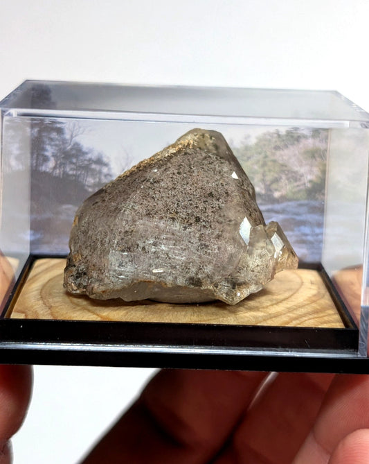 A translucent gray quartz crystal with a rough, natural surface and subtle internal reflections.