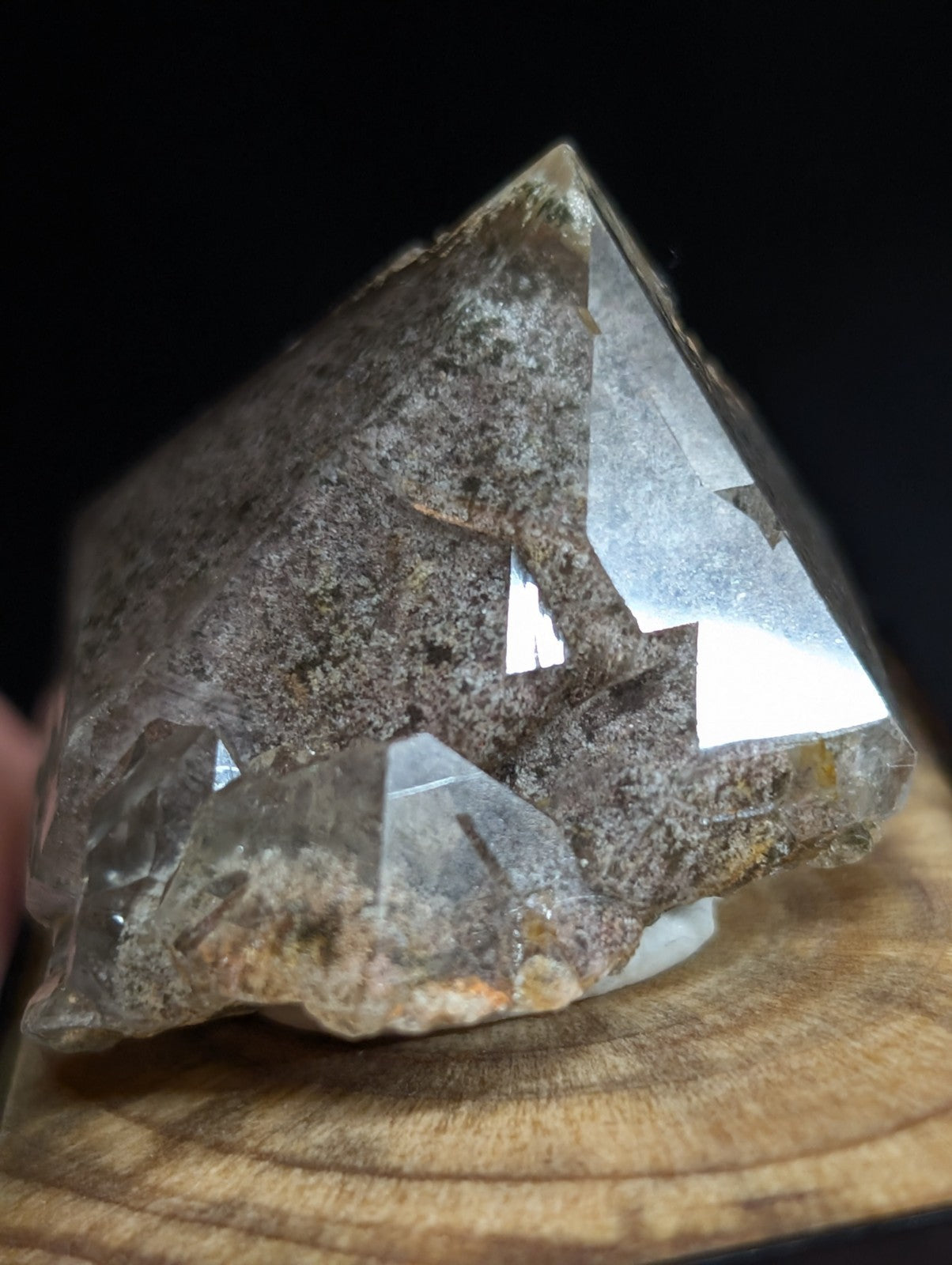 A translucent, faceted quartz crystal with a rough, earthy matrix and subtle golden inclusions.