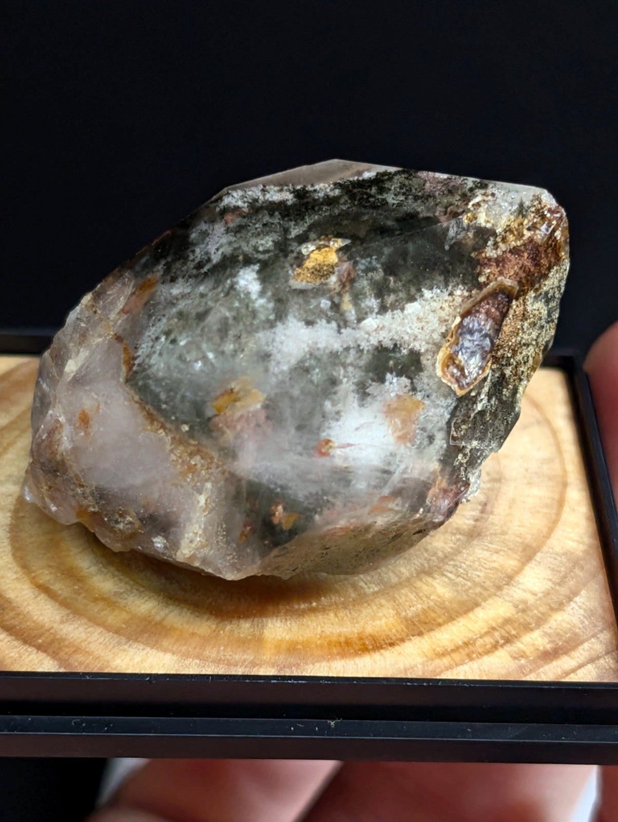 A translucent, irregularly shaped crystal specimen with a mix of gray, white, and earthy brown mineral inclusions.