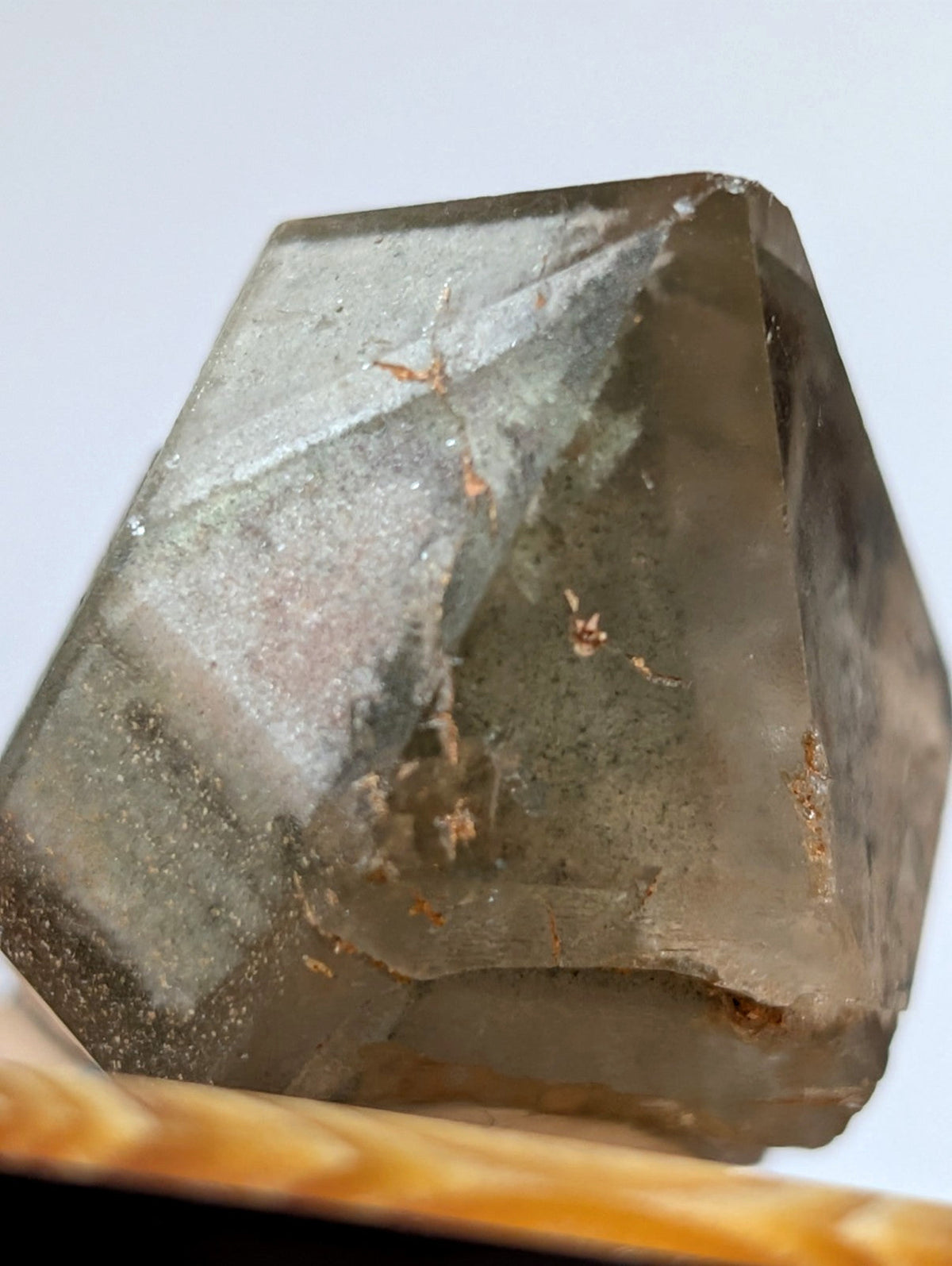 A translucent smoky quartz crystal with a geometric, faceted shape and subtle internal inclusions.