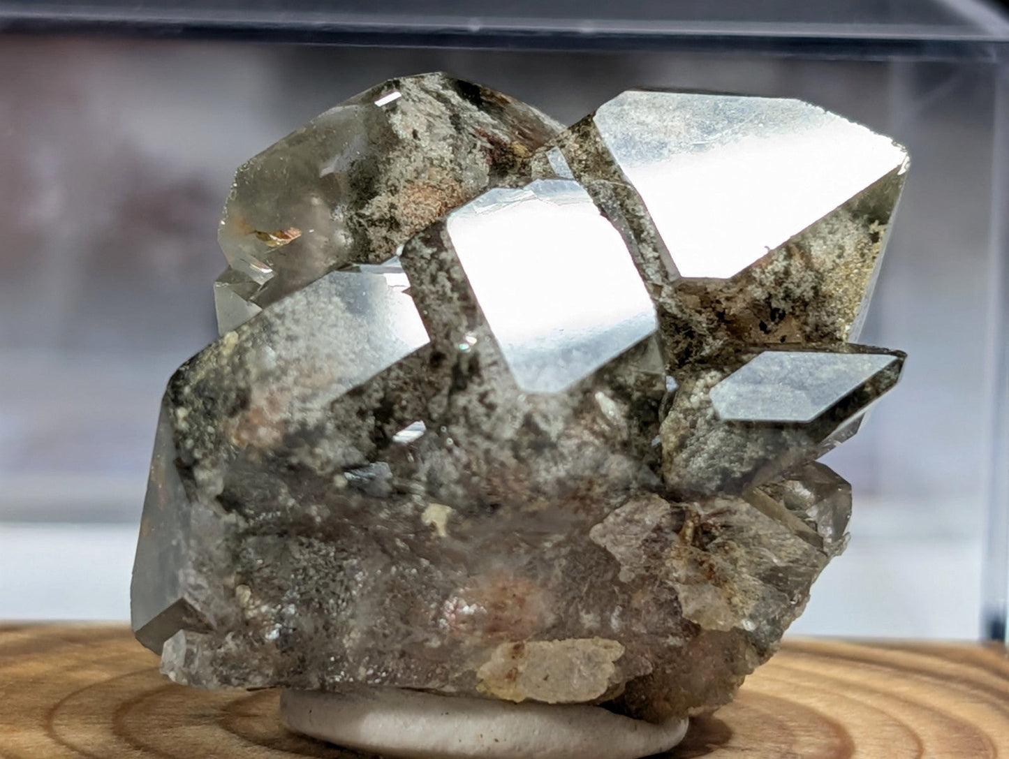 A cluster of metallic, reflective silver-colored crystals with a rough, earthy matrix.