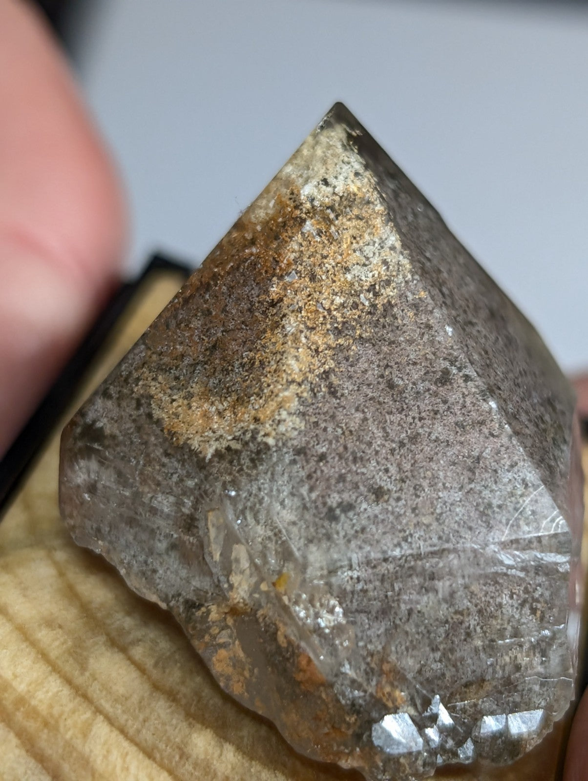 A translucent, pyramid-shaped crystal with a rough, earthy surface and subtle golden-brown mineral inclusions.