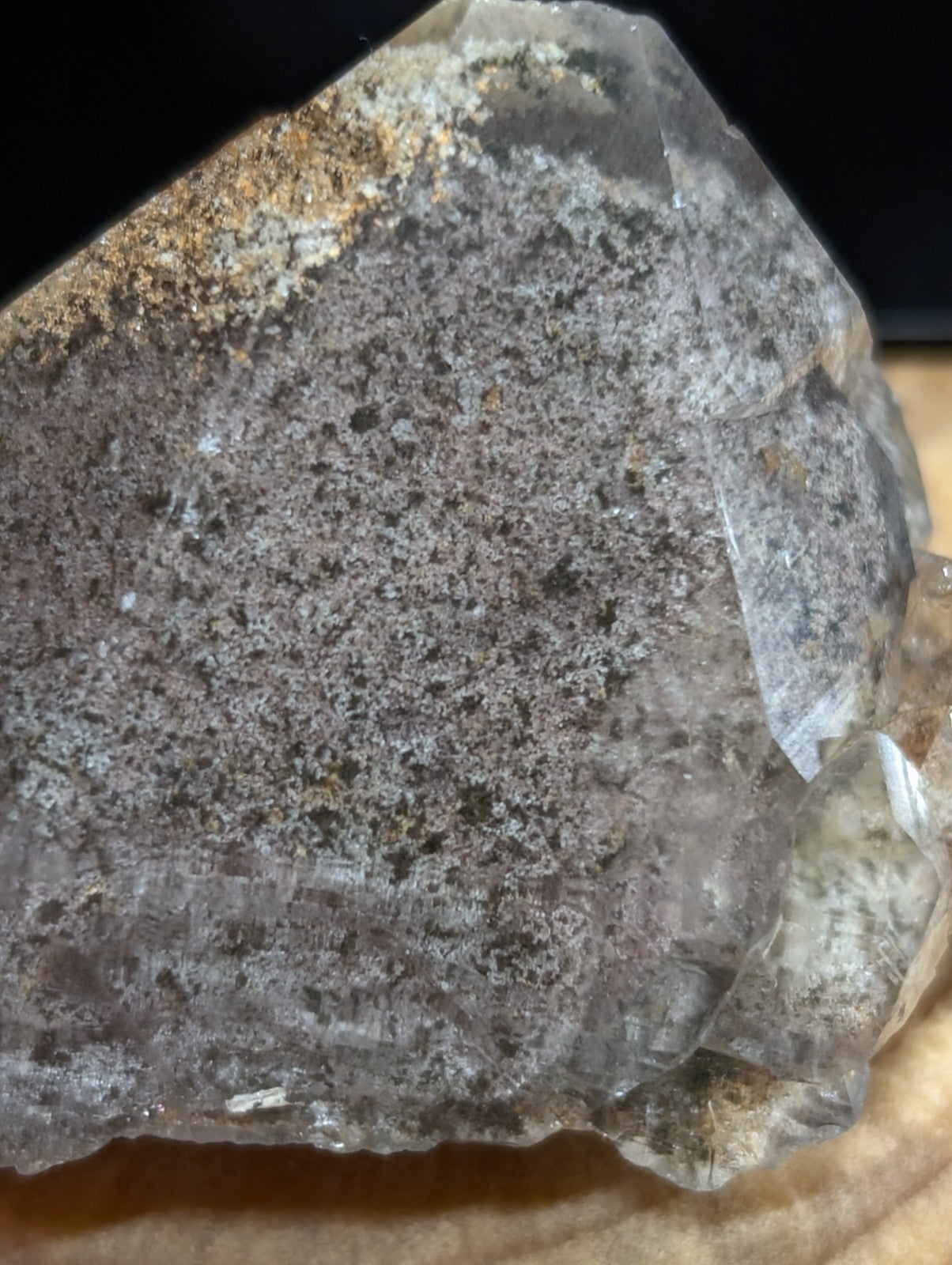 A translucent gray quartz crystal with a speckled, earthy surface and sharp geometric facets.