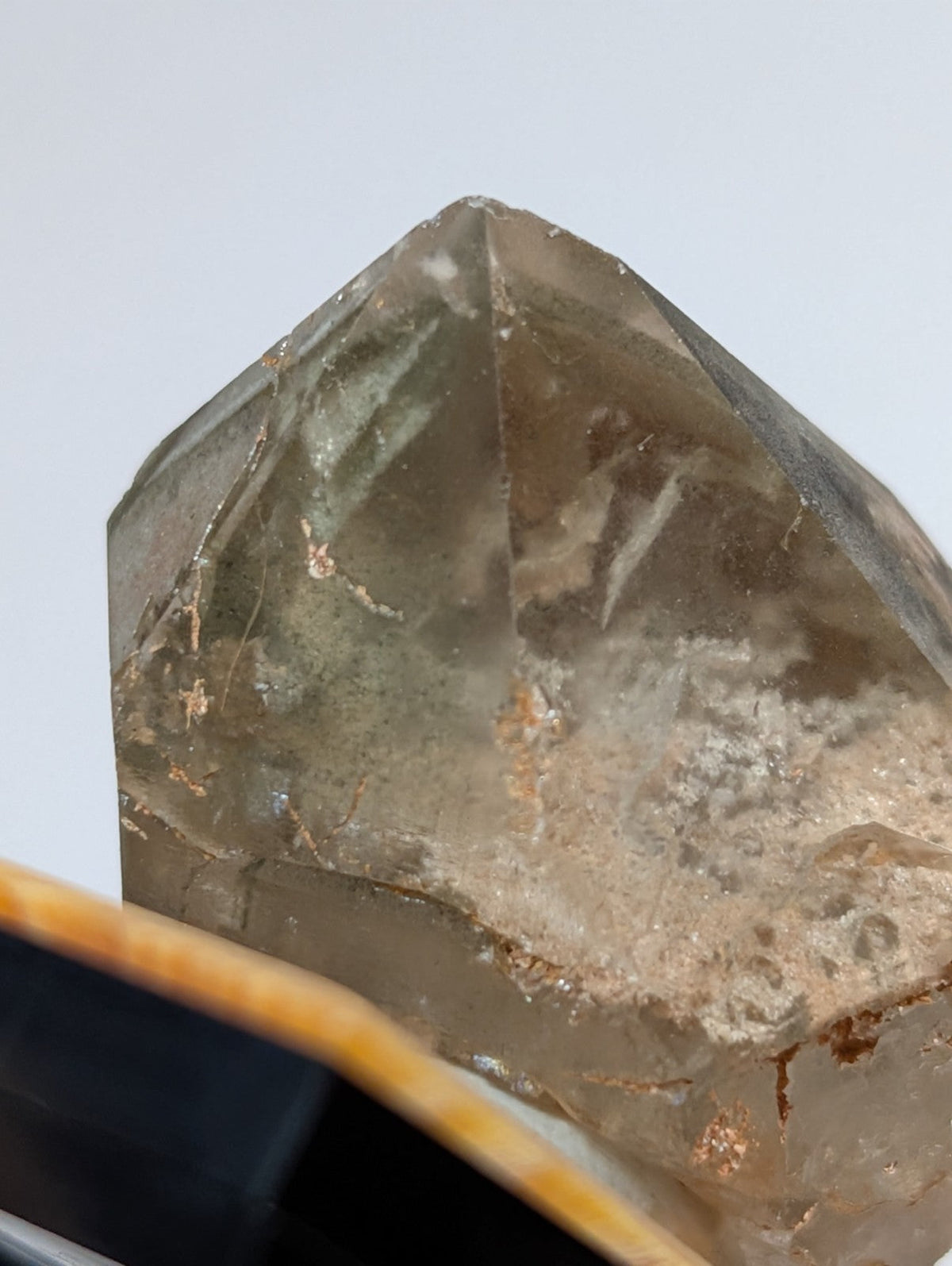 A translucent smoky quartz crystal with a pointed, faceted top and natural internal inclusions.