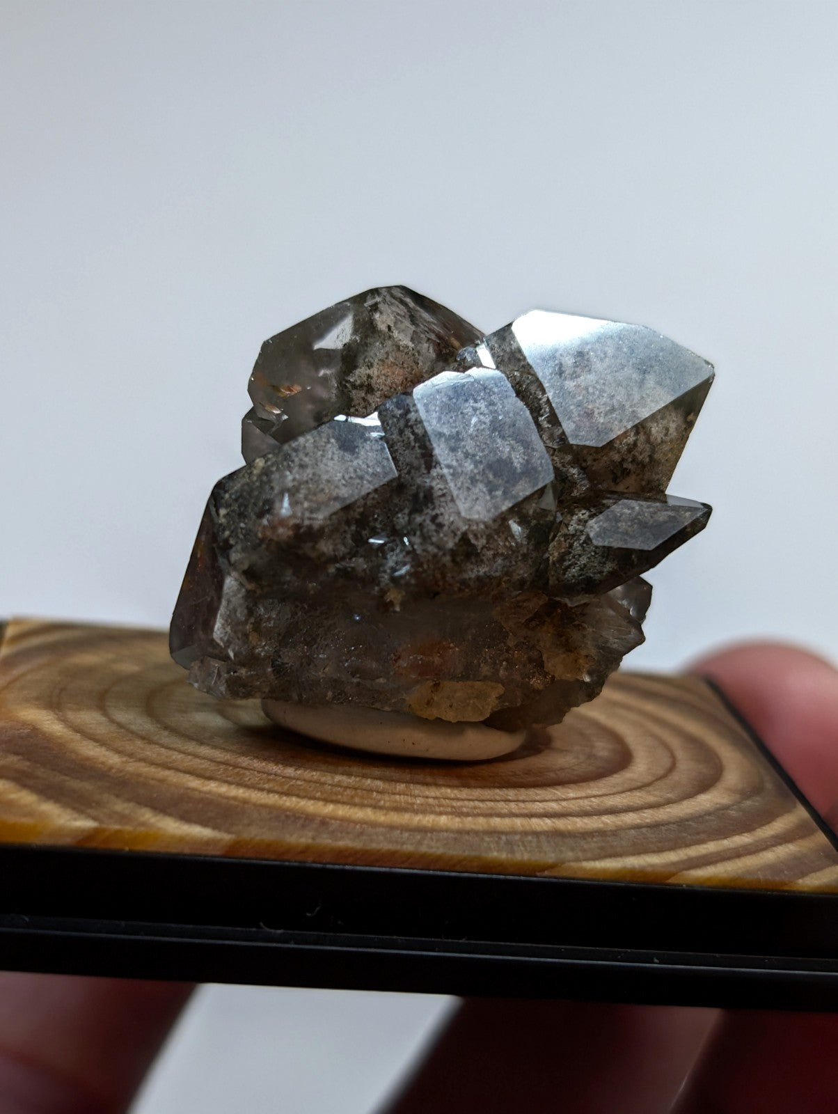 A cluster of dark, translucent quartz crystals with sharp geometric facets and a slightly rough, earthy base.