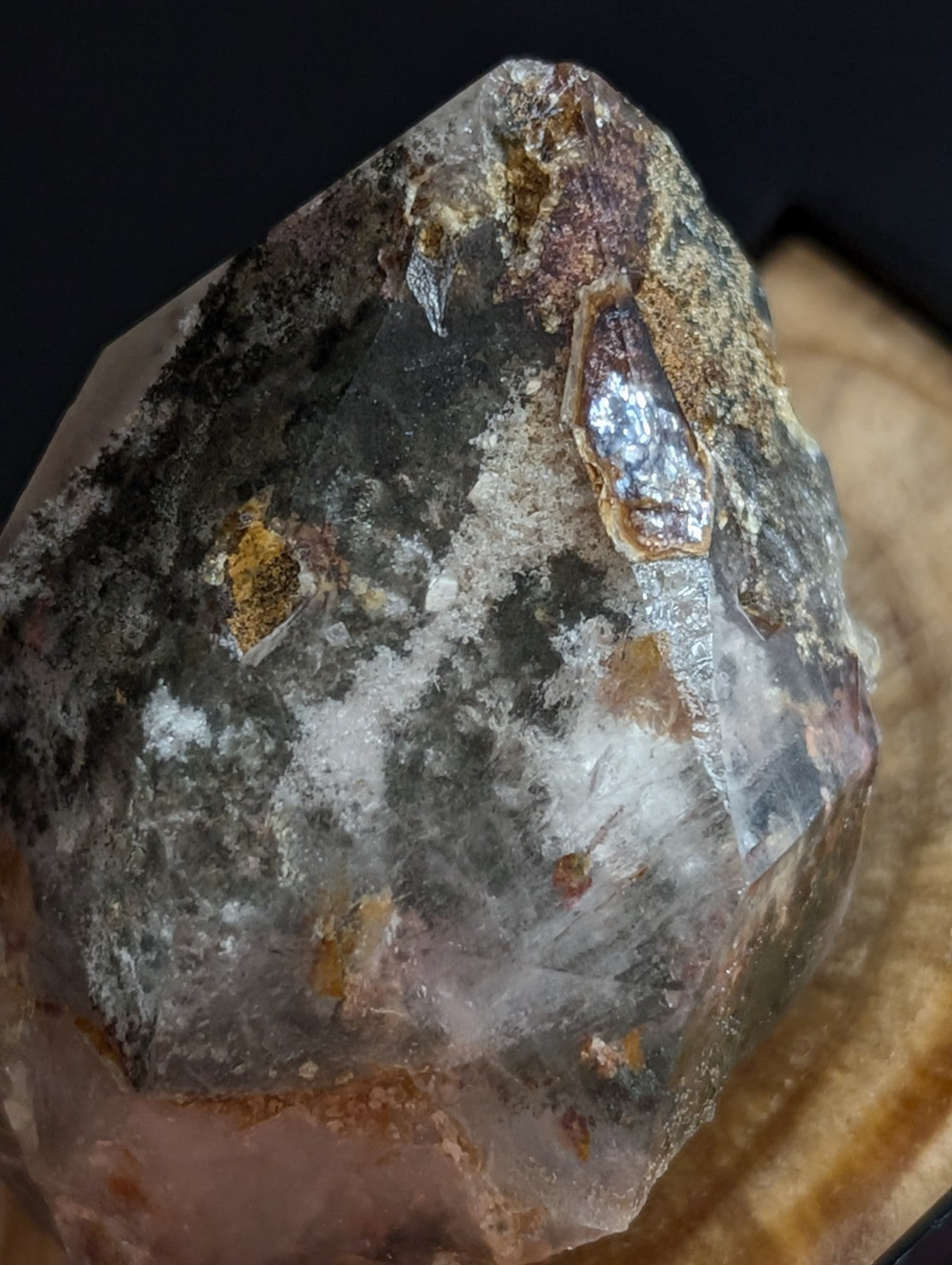 A translucent, multi-toned crystal with a rough, natural surface featuring patches of brown, yellow, and gray mineral inclusions.