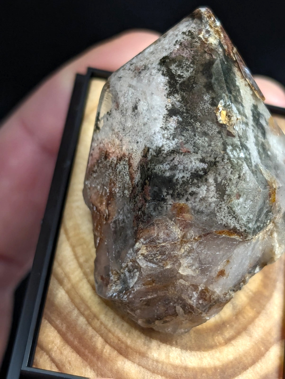 A translucent, faceted quartz crystal with natural mineral inclusions and earthy brownish-gray veining.