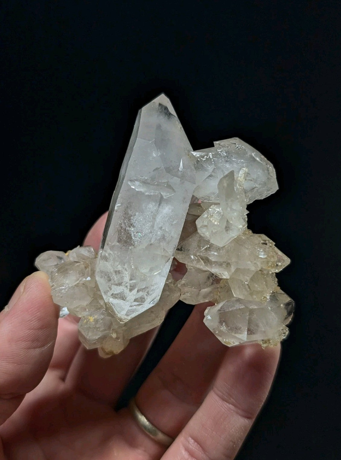 A translucent, clear quartz crystal cluster with a prominent pointed spike and smaller surrounding crystals.