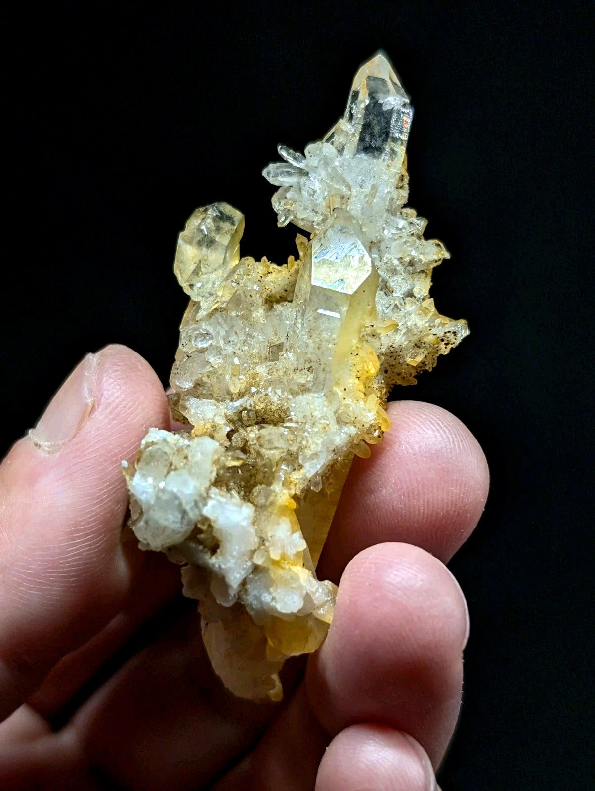 A translucent yellow and clear quartz crystal cluster with a rough, earthy matrix.