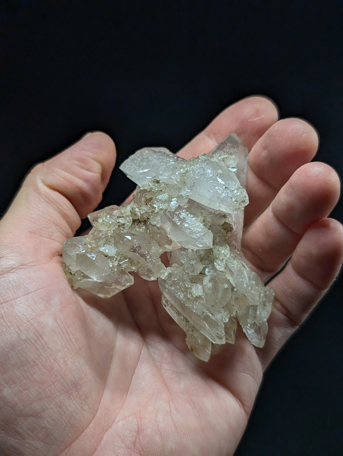 A cluster of translucent, clear quartz crystals with sharp, faceted edges and a slightly cloudy appearance.