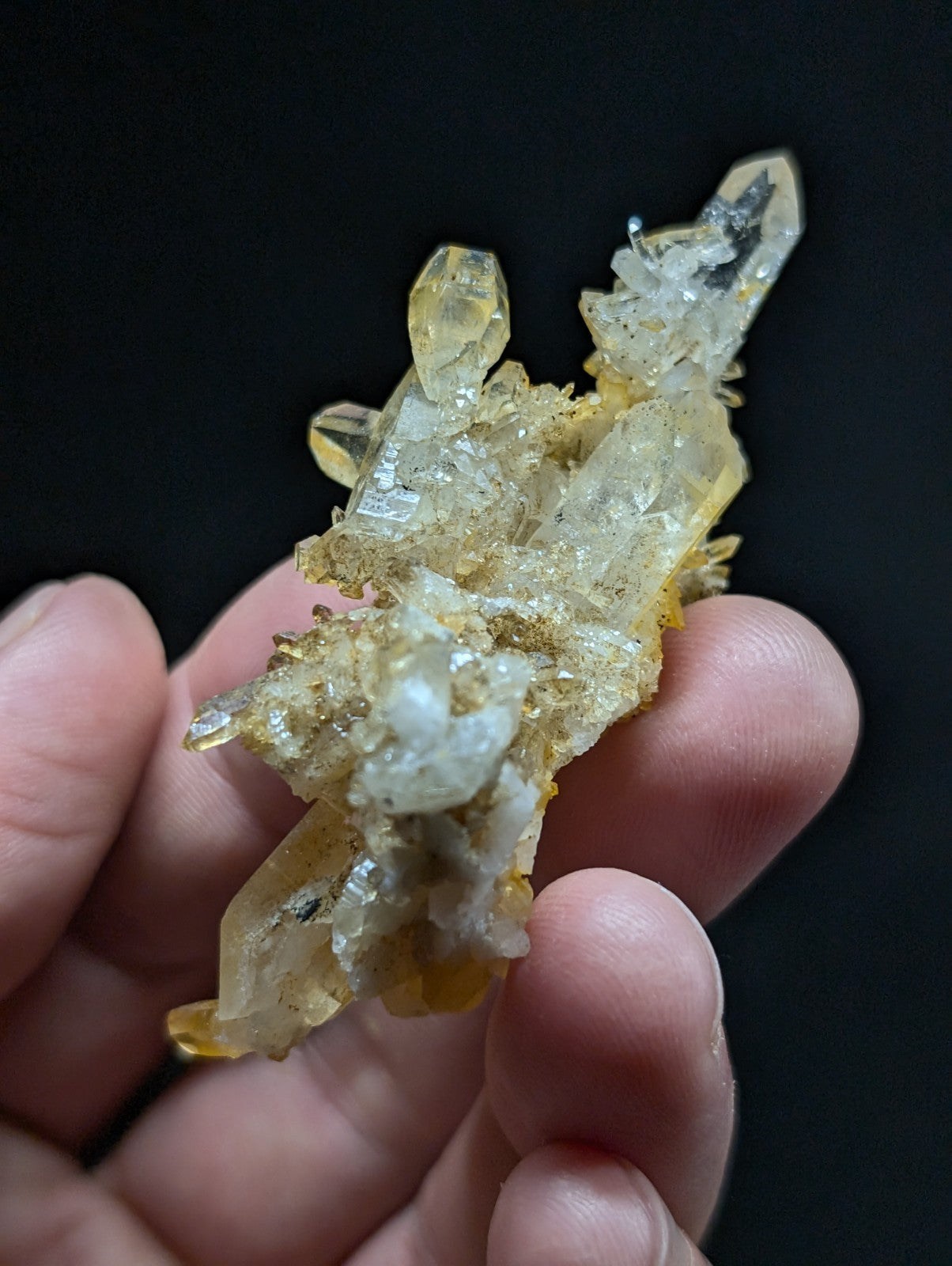 A translucent yellow and clear quartz crystal cluster with a rough, earthy base.