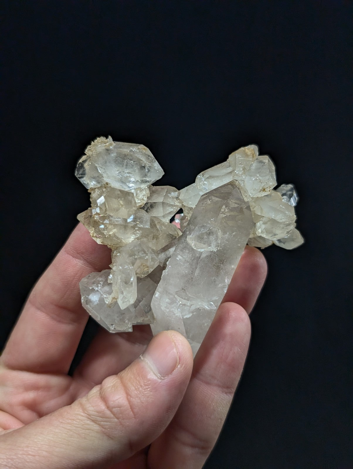 A cluster of translucent, clear quartz crystals with natural facets and subtle yellowish tints.