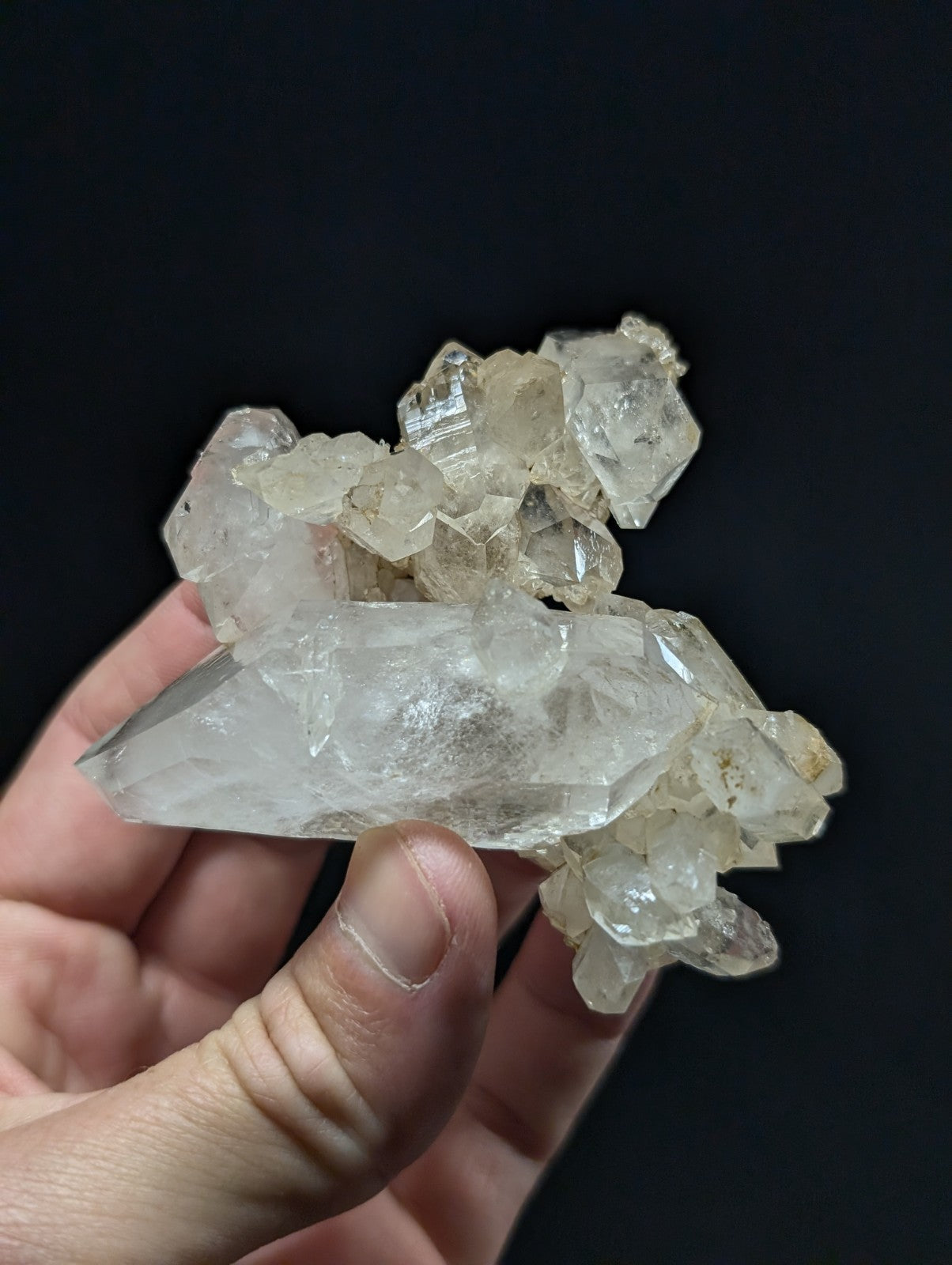 A translucent, clear quartz crystal cluster with a mix of sharp-edged and rounded facets.
