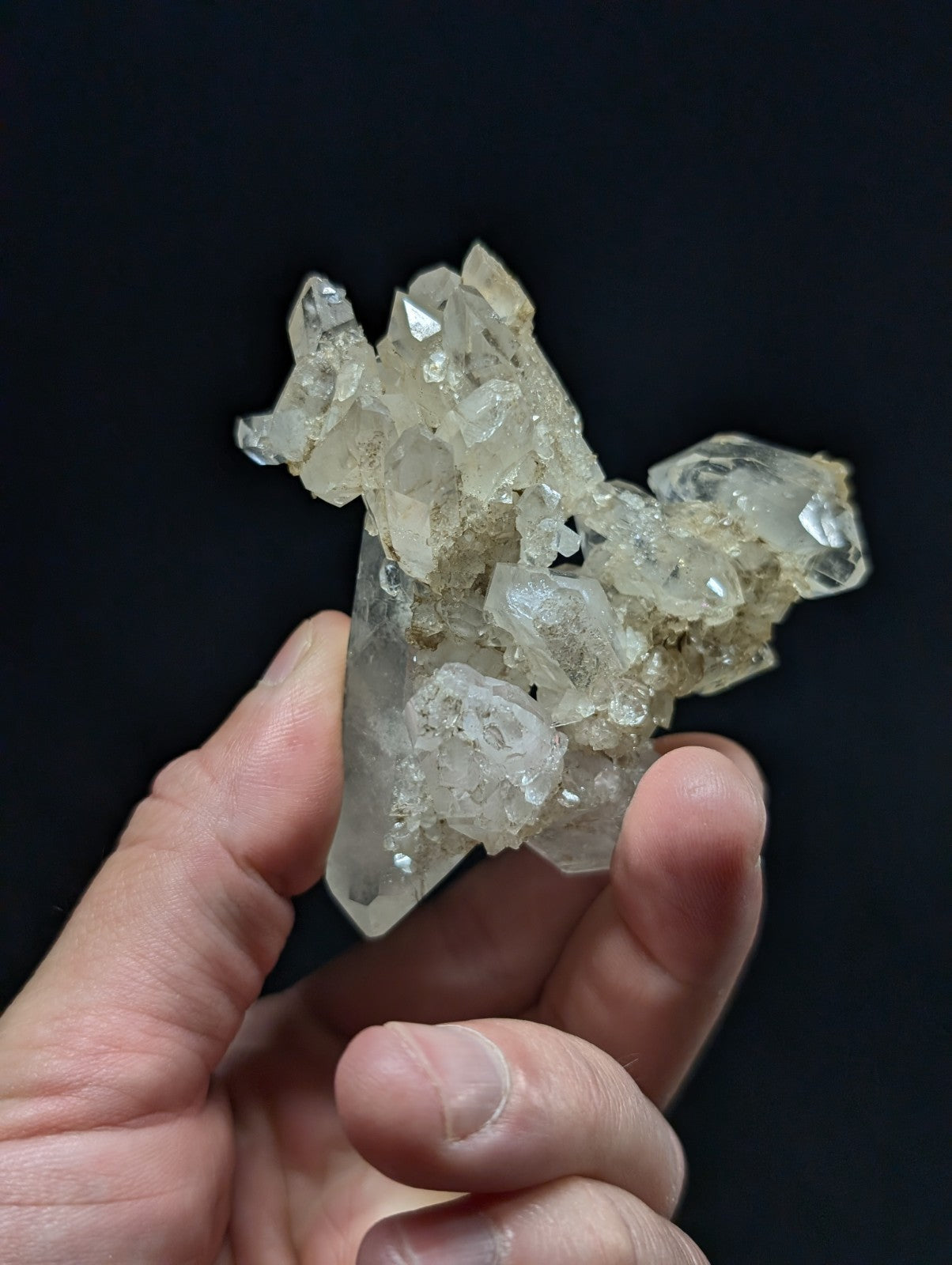 A translucent, clear quartz crystal cluster with sharp facets and a slightly cloudy base.