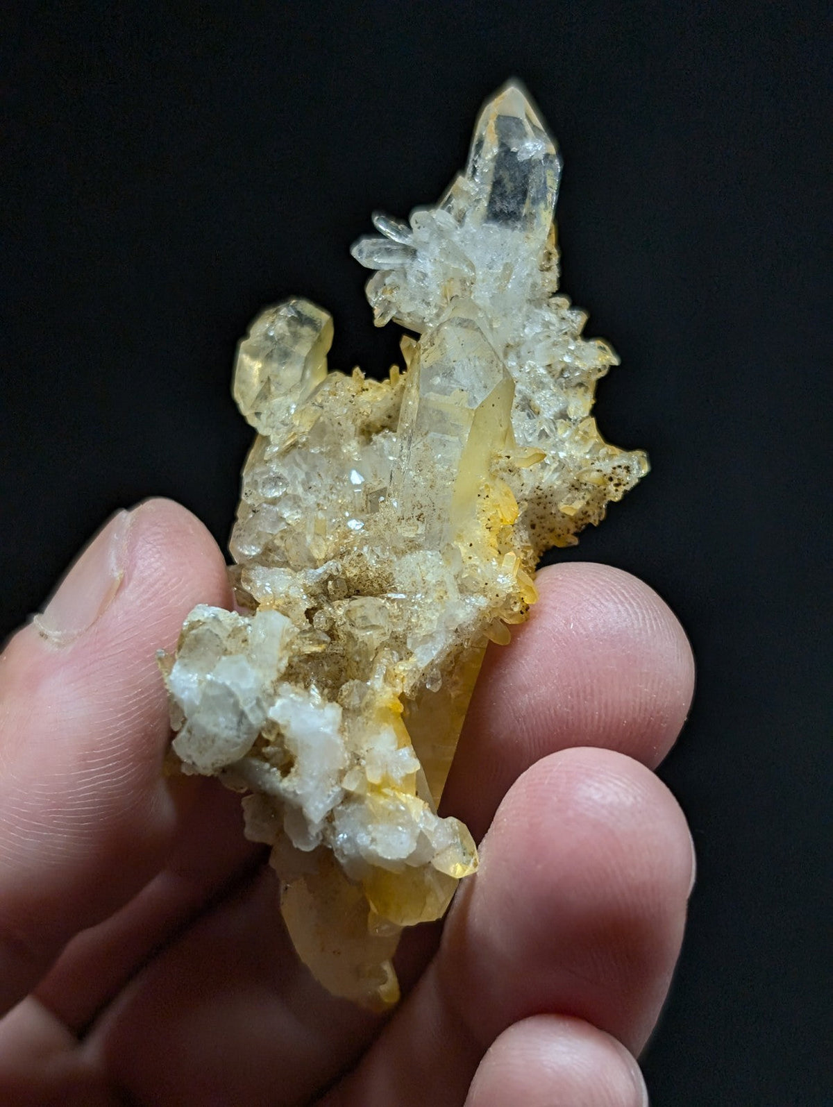 A translucent yellow and clear quartz crystal cluster with a rough, earthy base.
