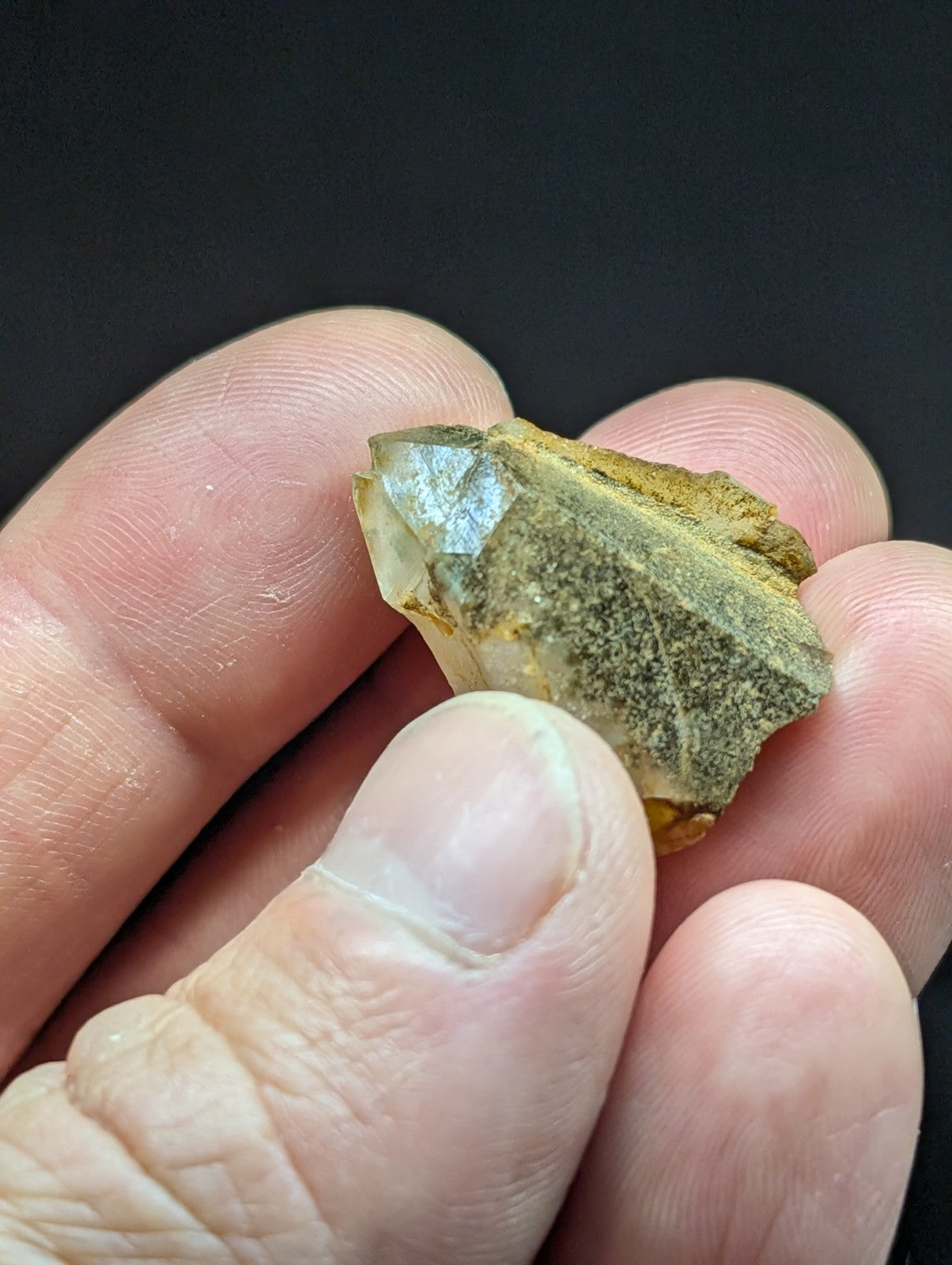 A translucent, faceted crystal with a golden-brown matrix and subtle greenish hues.