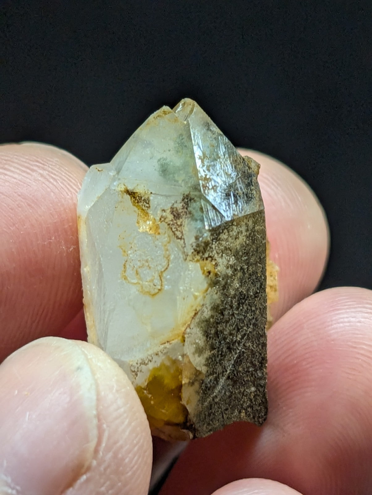 A translucent, pale green quartz crystal with natural inclusions and a rough, earthy base.