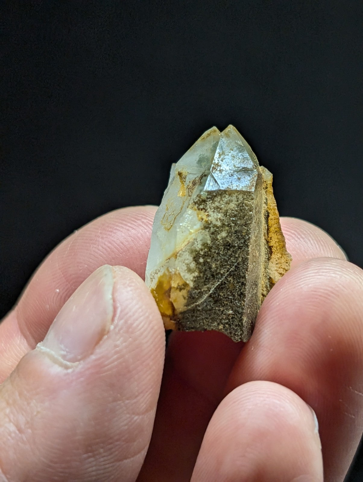 A translucent, pale yellowish quartz crystal with a pointed tip and natural matrix of brown and golden hues.