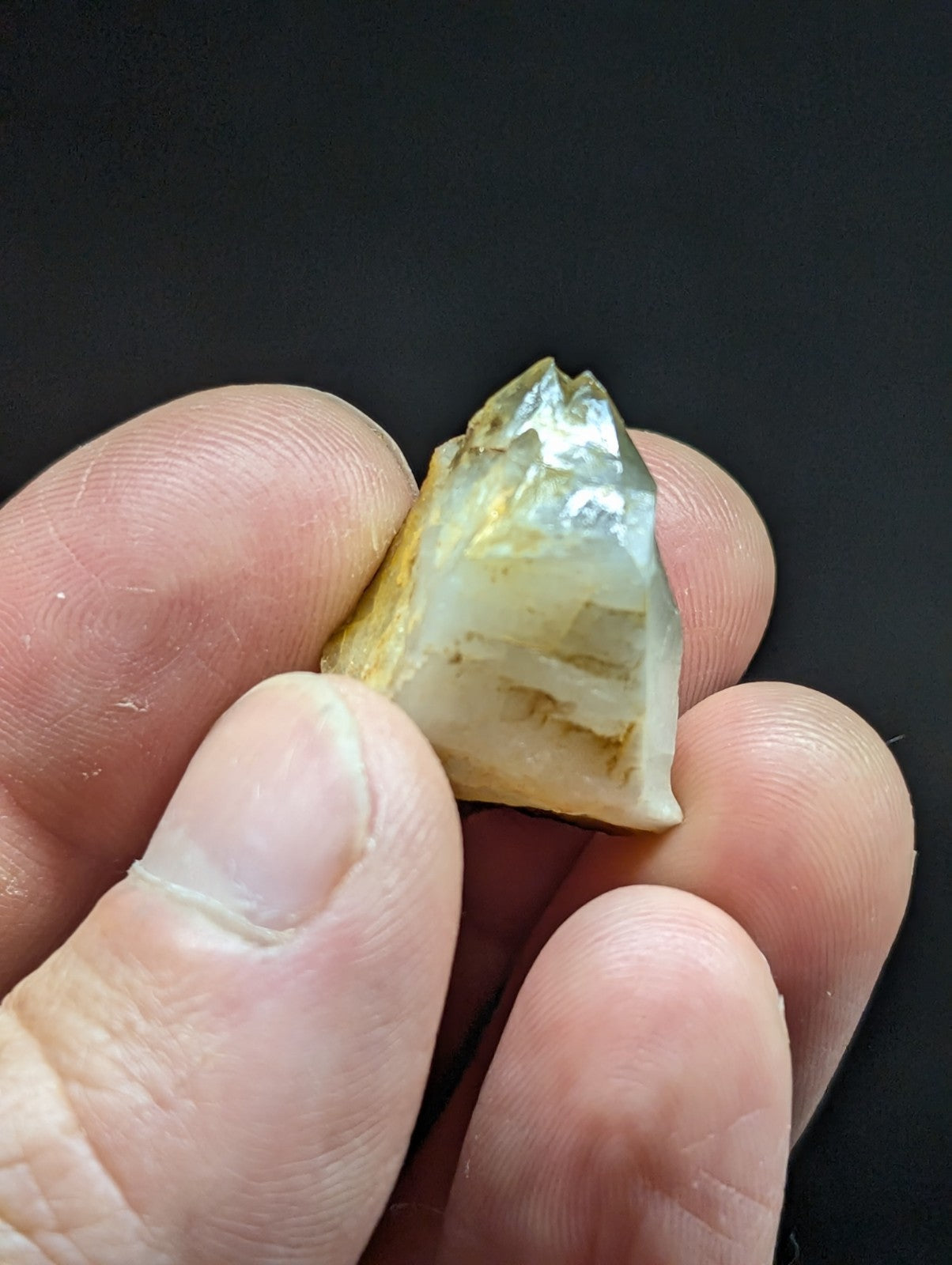 A translucent, triangular crystal with a pale yellowish tint and visible internal striations.