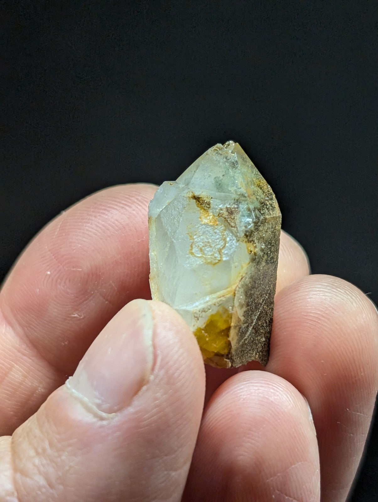A translucent, pale yellowish-white quartz crystal with natural inclusions and a rough, earthy base.
