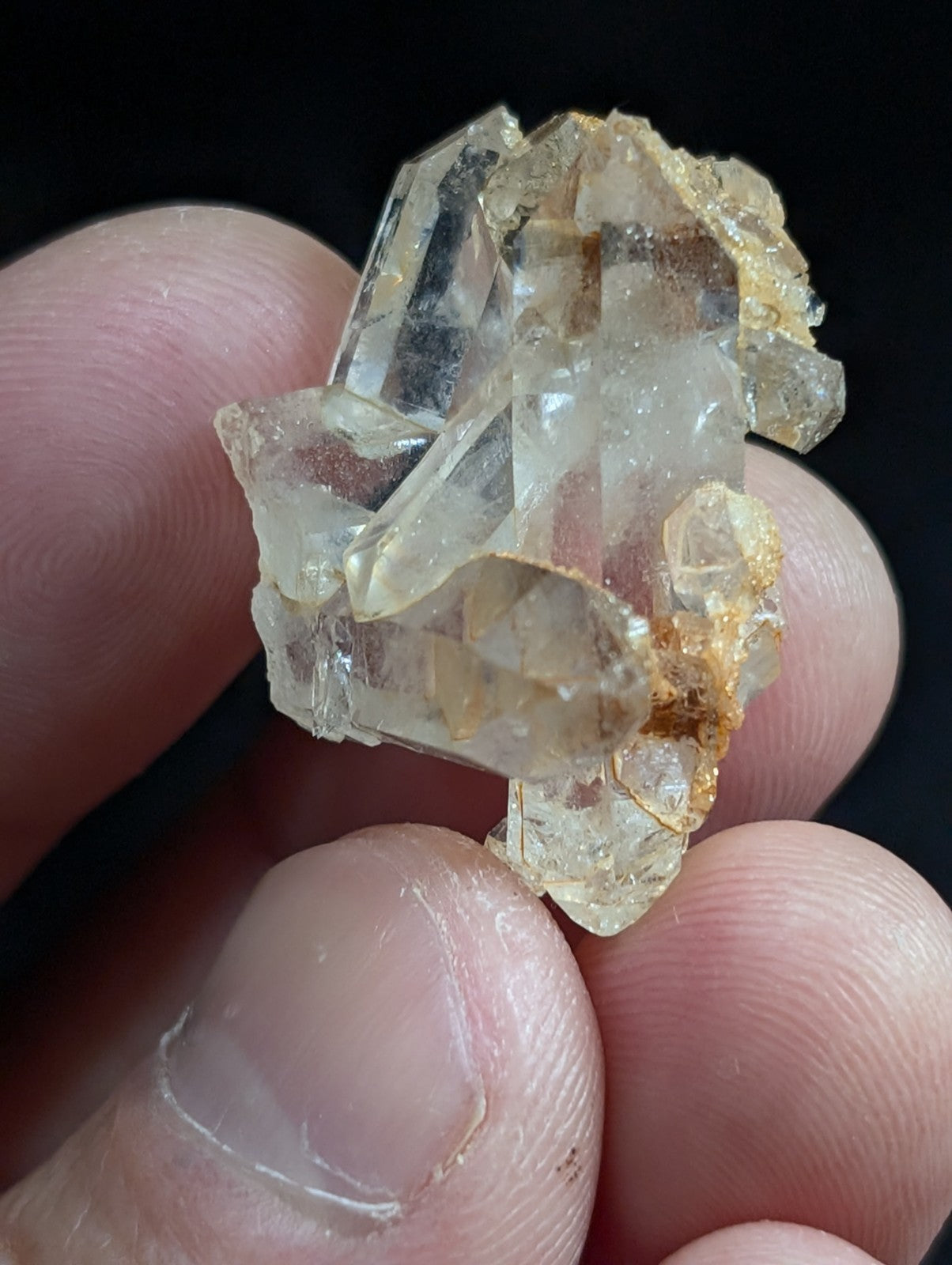A cluster of translucent, pale yellowish quartz crystals with sharp geometric facets and some golden-brown mineral inclusions.