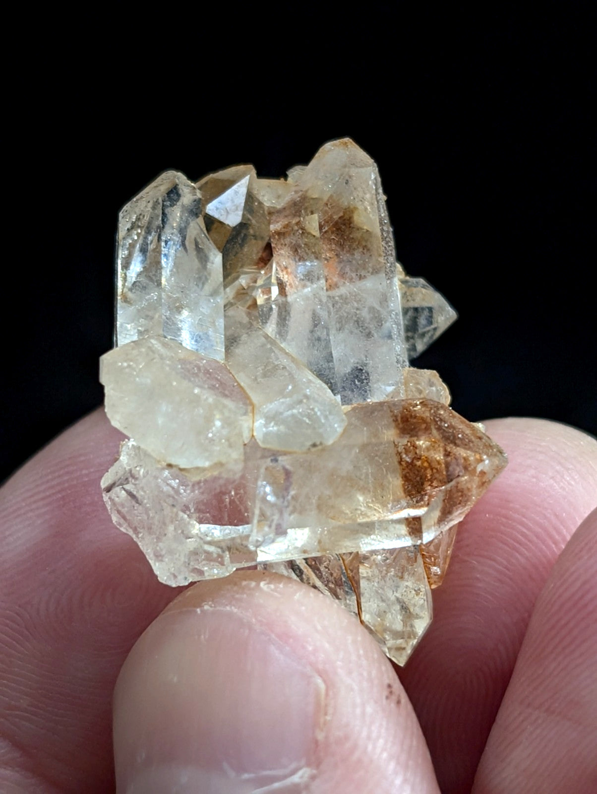 A cluster of translucent, pale yellowish quartz crystals with some brown inclusions.