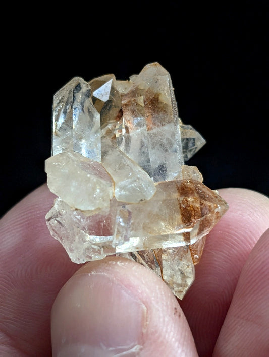 A cluster of translucent, pale yellowish quartz crystals with some brown inclusions.