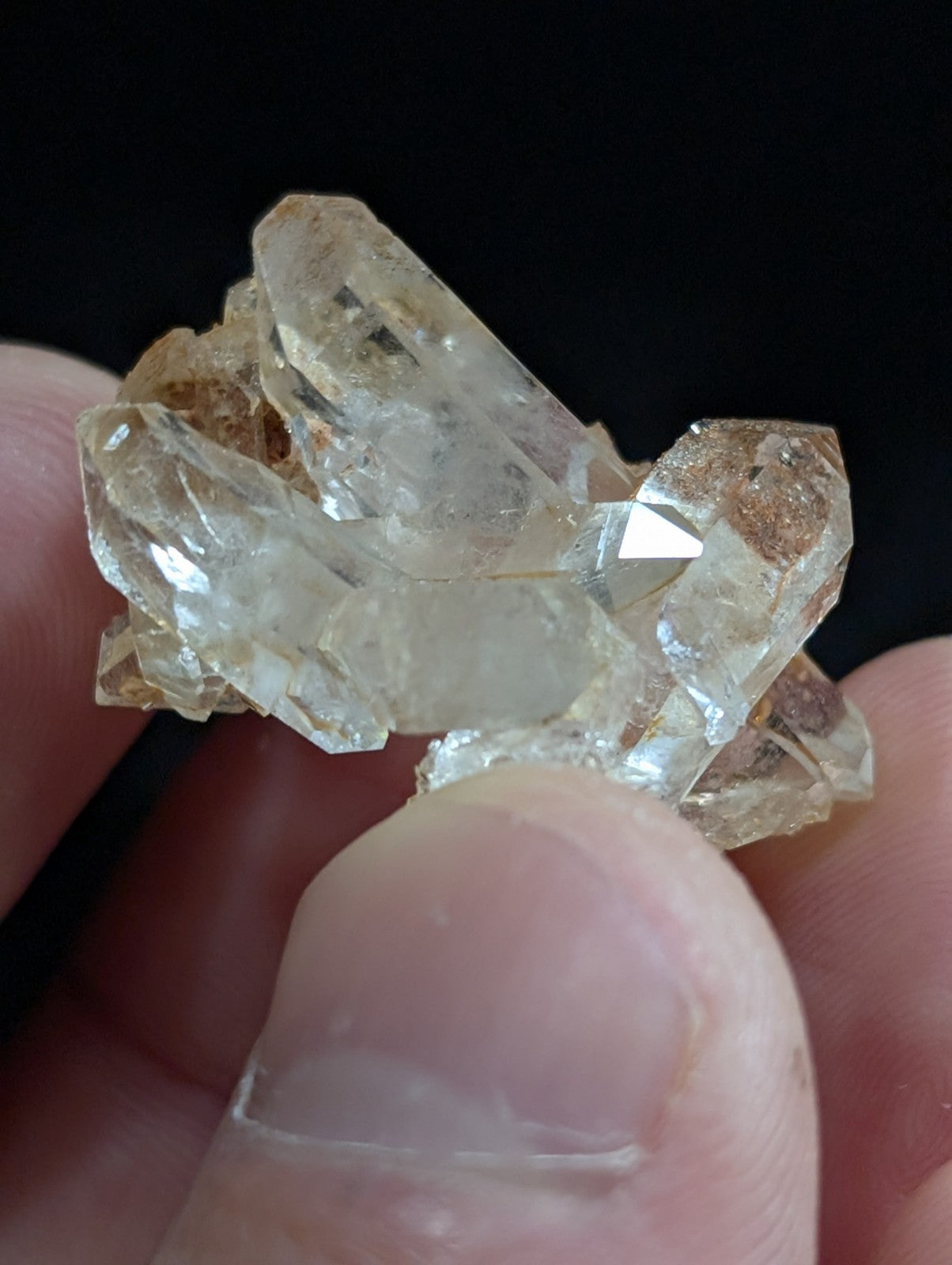 A cluster of translucent, pale yellow quartz crystals with sharp geometric facets and subtle brownish inclusions.