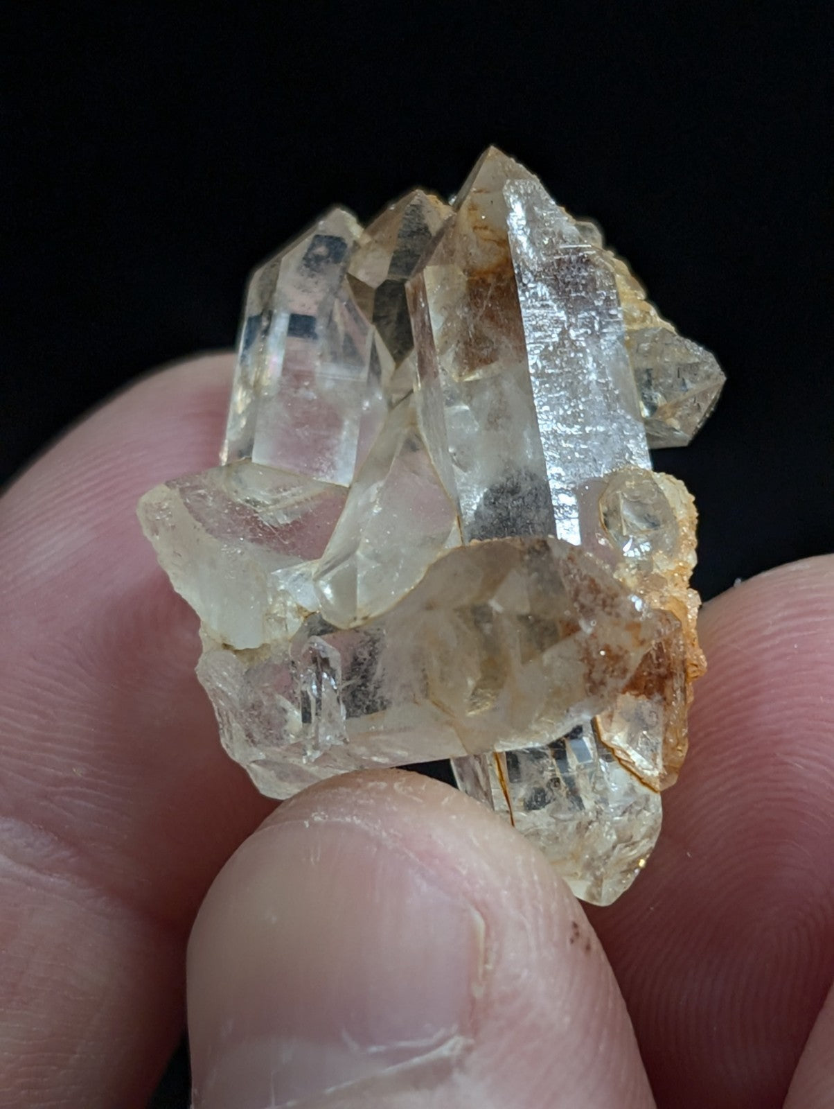 A cluster of translucent, pale yellowish quartz crystals with sharp facets and some amber-tinted inclusions.