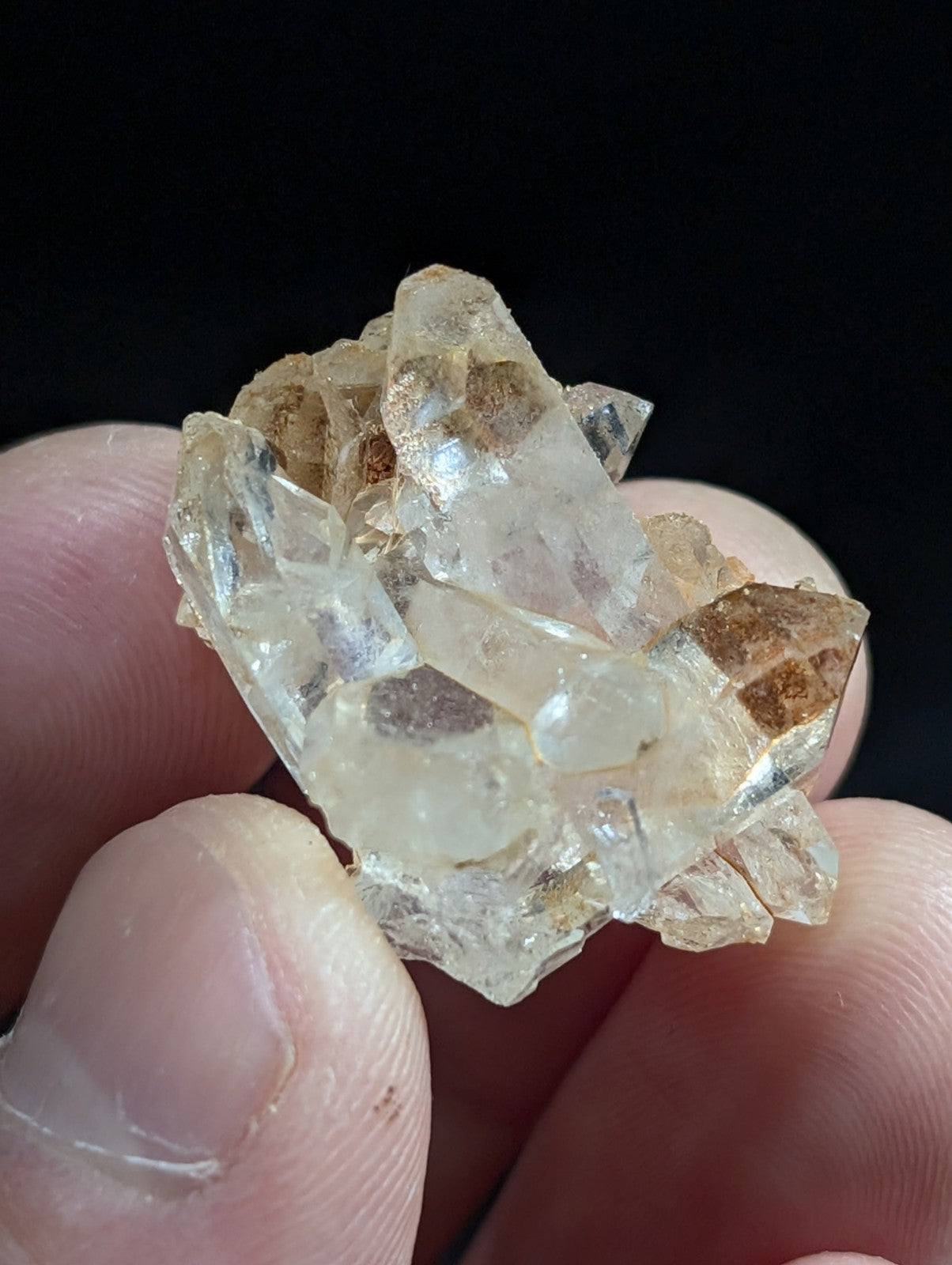 A cluster of translucent quartz crystals with clear, faceted points and subtle amber-brown inclusions.