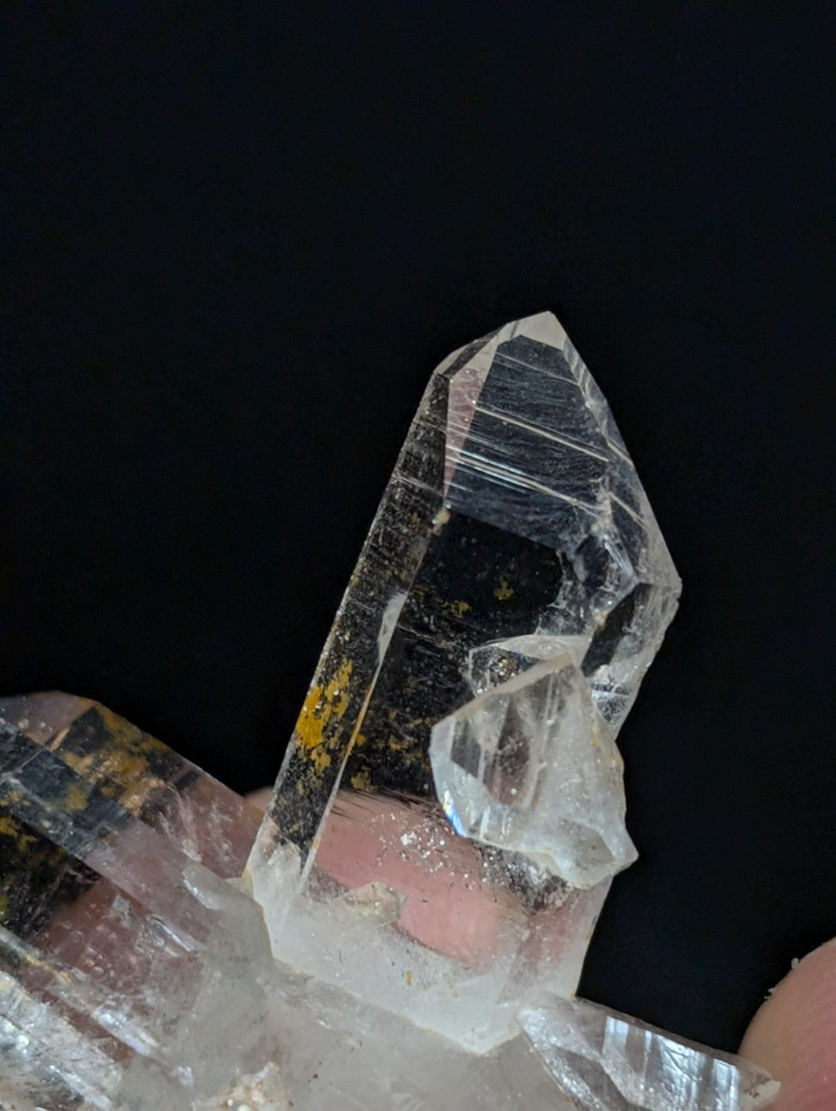A clear quartz crystal cluster with sharp, faceted points and subtle internal striations.